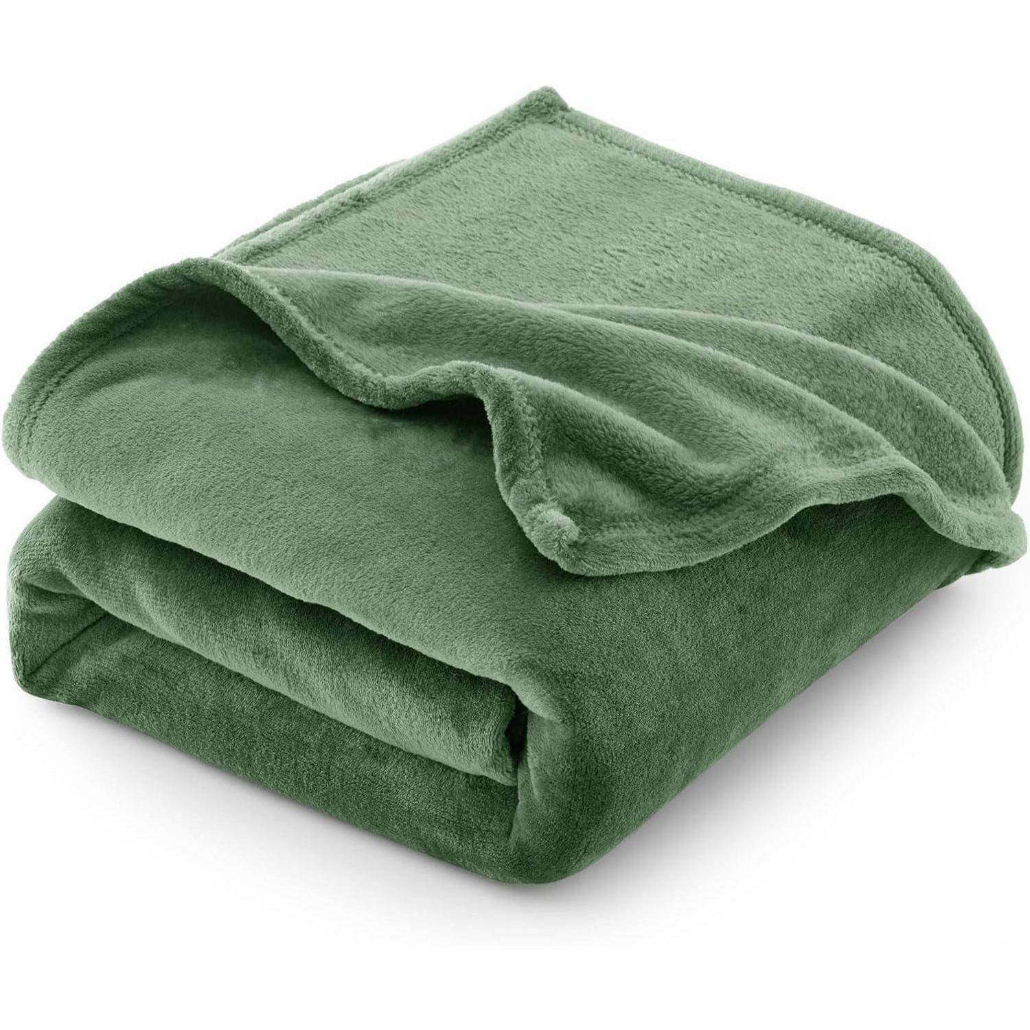 Eine plüschige, gefaltete grüne Decke aus weichem Material, die vor einem schlichten weißen Hintergrund gezeigt wird.