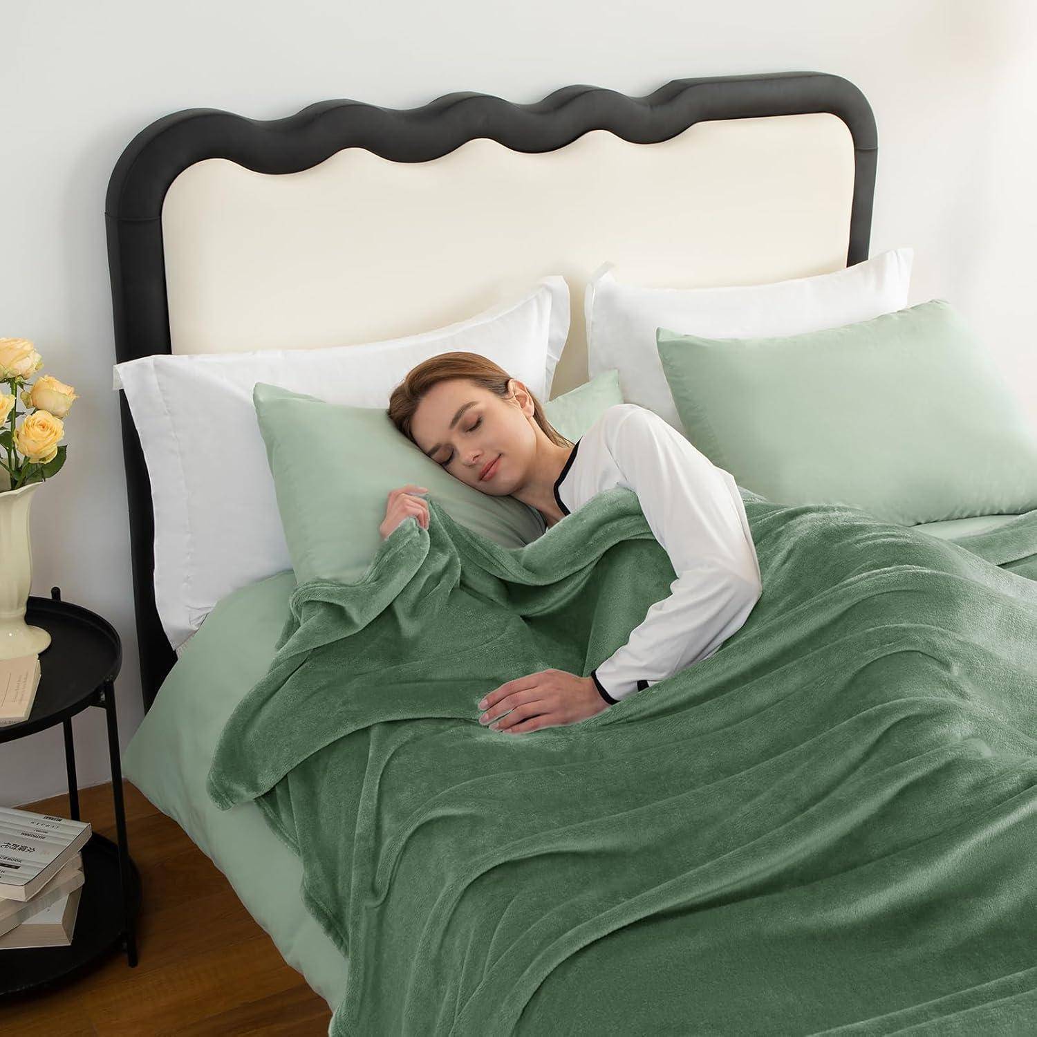 Eine Frau ruht friedlich in einem ordentlich gemachten Bett mit grünen Decken und weißen Kissen, was Komfort und Entspannung vermittelt.