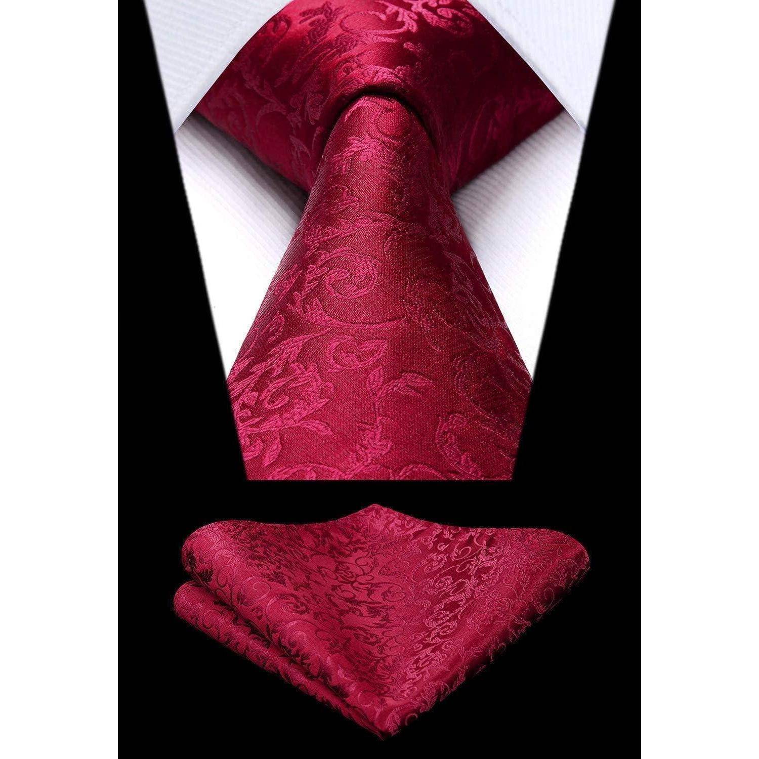 Eine rote paisleymusterierte Krawatte und das passende Einstecktuch auf einem weißen Hemd und einem schwarzen Anzug, ordentlich arrangiert für eine formelle Kleidungsdarstellung.