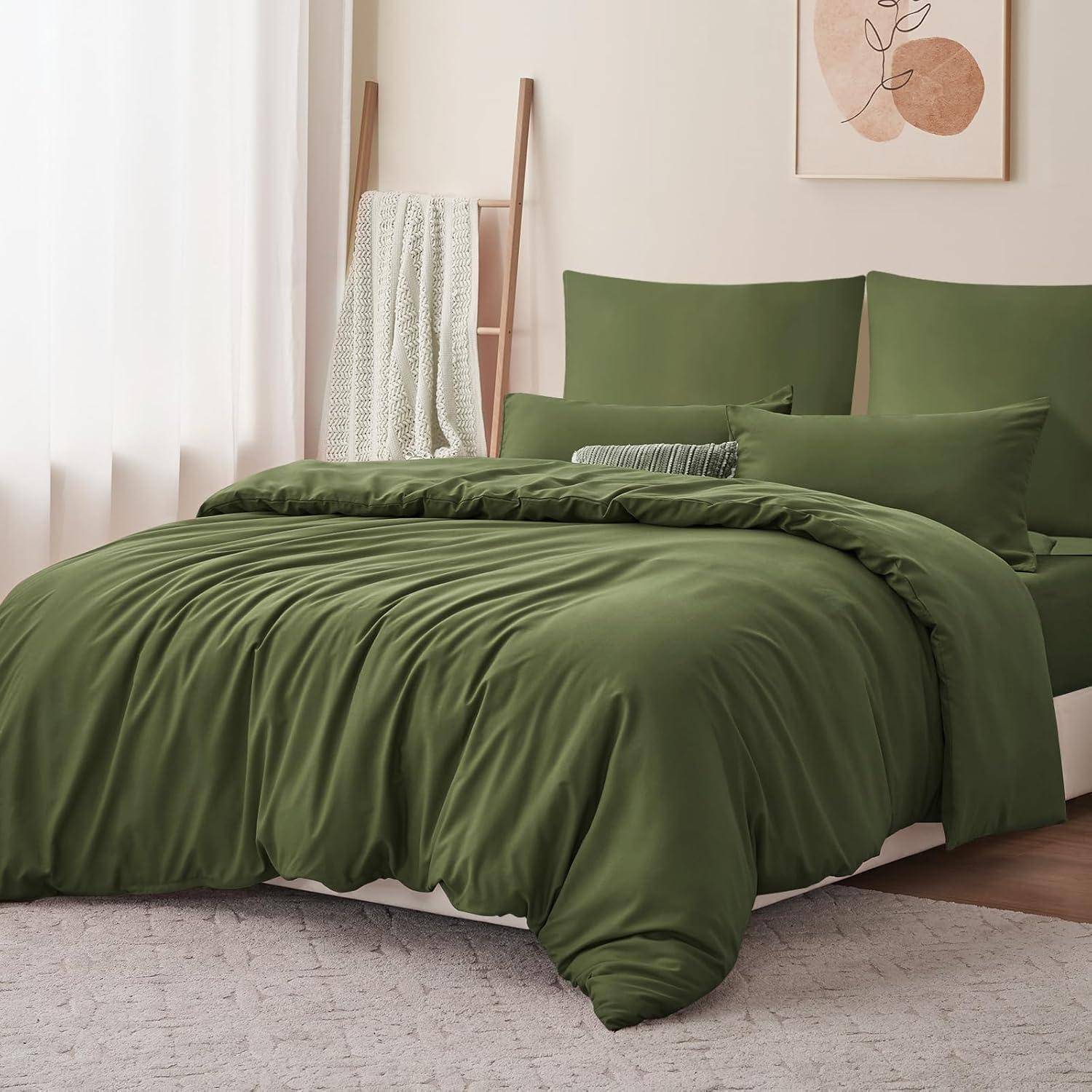 Ein sauber gemachtes Bett mit einem grünen Bettüberwurf und passenden Kissen, neben einer sich lehnenden Holzleiter, die eine weiße strukturierte Decke trägt.