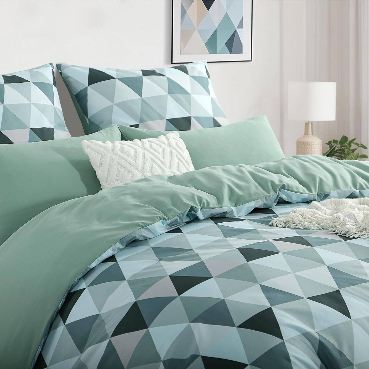 Geometrisch gemusterte Bettwäsche und Kissen in Blau- und Grüntönen, mit einem weißen Akzenzkissen und einer weichen grünen Decke auf einem Bett.