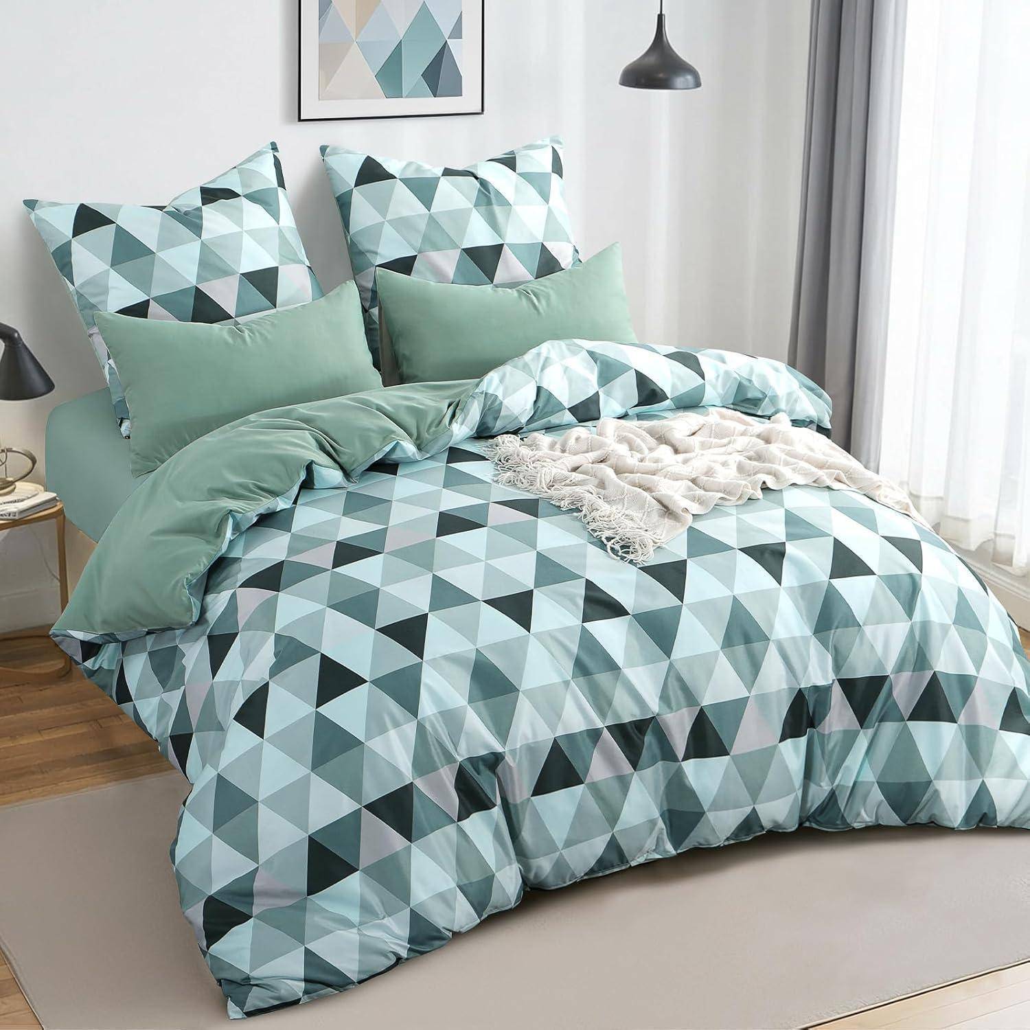 Ein ordentlich gemachtes Bett mit geometrischem Bettwäsche-Muster in Grün- und Blautönen, zwei passenden Kissen und einem gerahmten abstrakten Kunstwerk darüber.