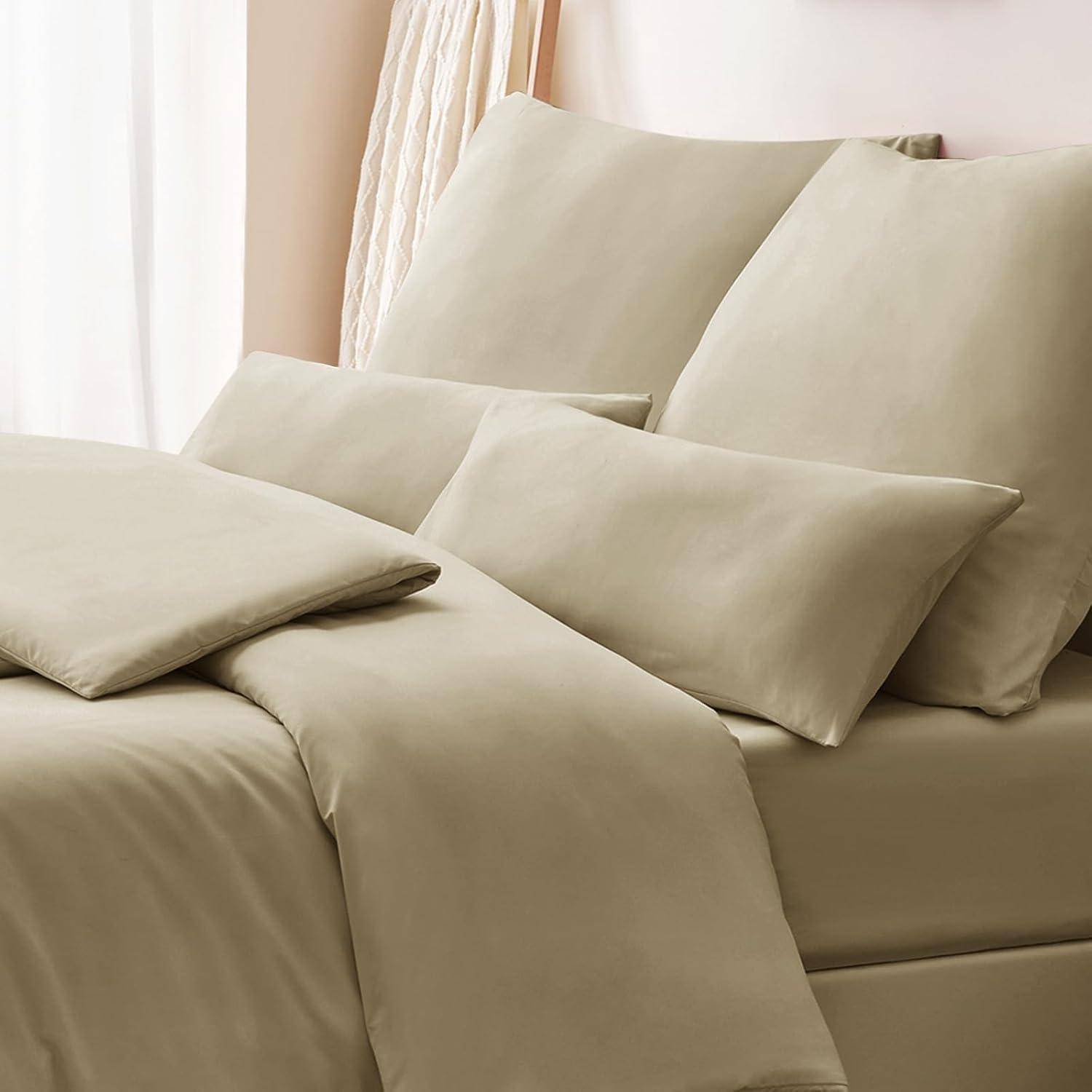 Ein ordentlich gemachtes Bett mit beigen Laken, Kissen und einer Bettdecke, das sich in einem sanft beleuchteten Raum mit Gardinen im Hintergrund befindet.