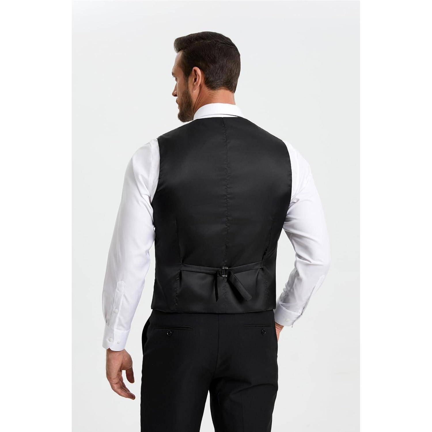 Ein Mann in formeller Kleidung, der eine schwarze Weste über einem weißen Hemd und schwarzen Hosen trägt, ist von hinten vor einem schlichten Hintergrund zu sehen.