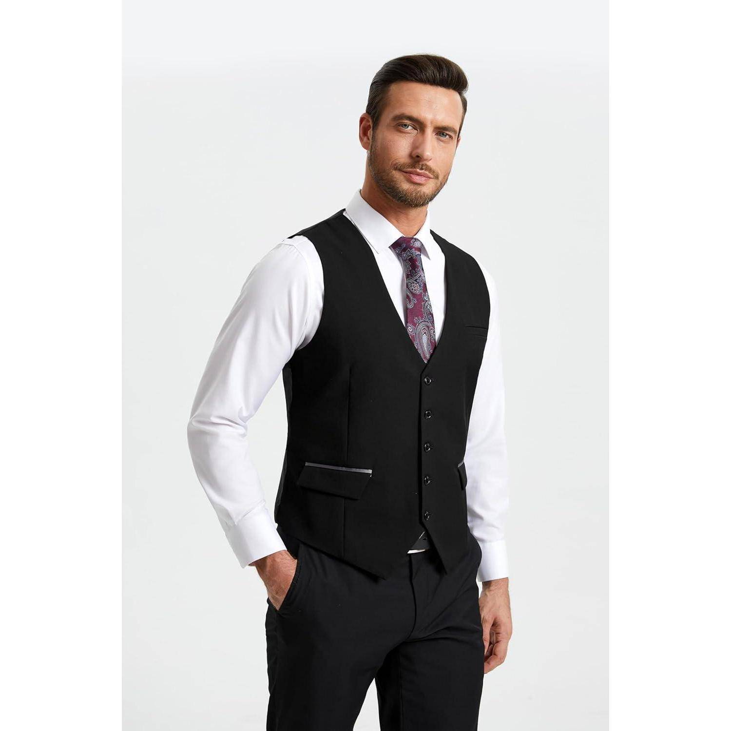 Ein Mann in einem formellen Outfit mit einer schwarzen Weste und Krawatte über einem weißen Hemd, der vor einem schlichten Hintergrund steht.