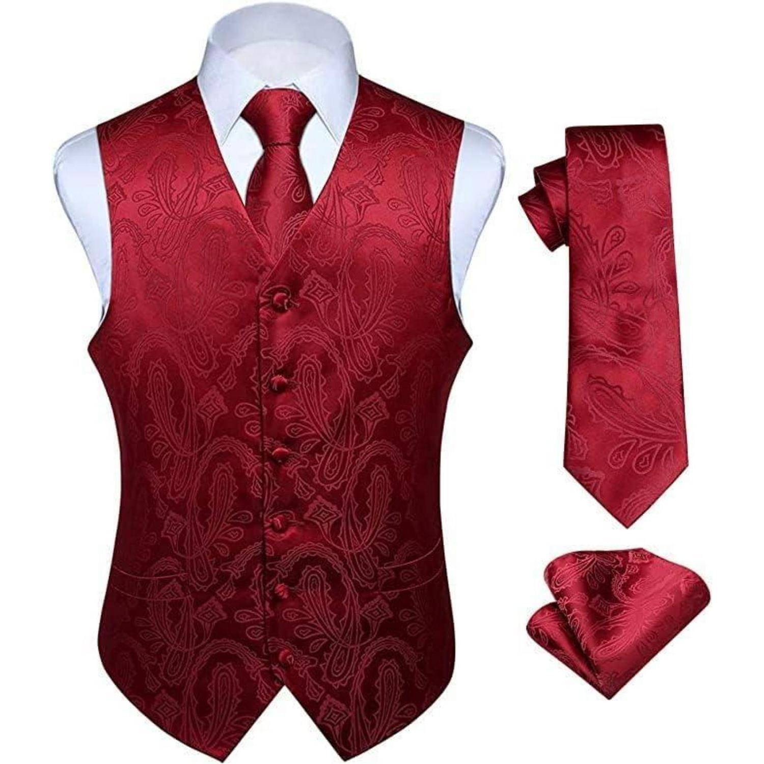 Ein aufeinander abgestimmtes Set bestehend aus einer roten Paisley-gemusterten Weste, einer Krawatte, einem Einstecktuch und Manschettenknöpfen auf einem weißen Hemd, präsentiert vor einem einfarbigen Hintergrund.