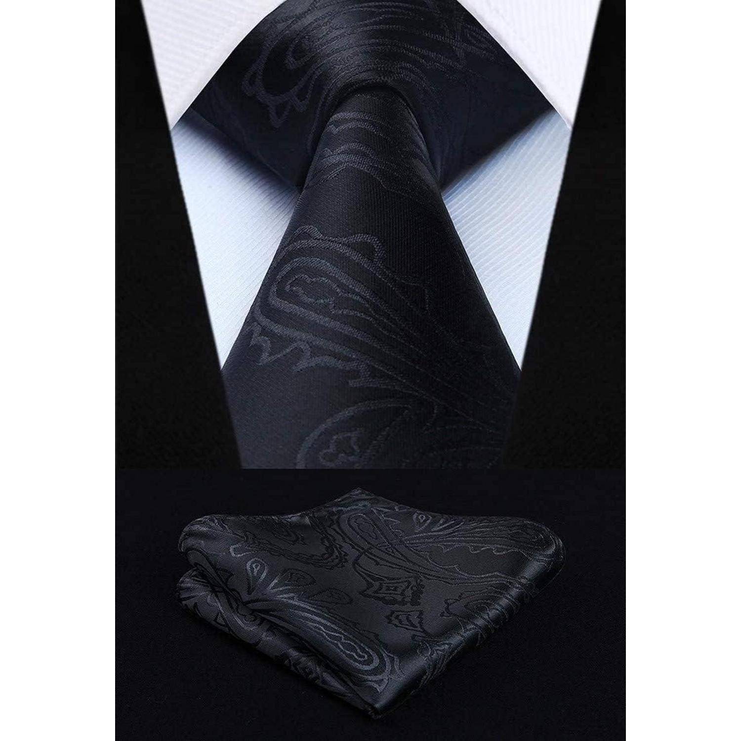Eine schwarze Krawatte mit einem dezenten Paisleymuster, kombiniert mit einem passenden Einstecktuch, präsentiert vor einem weißen Hemd auf dunklem Hintergrund.