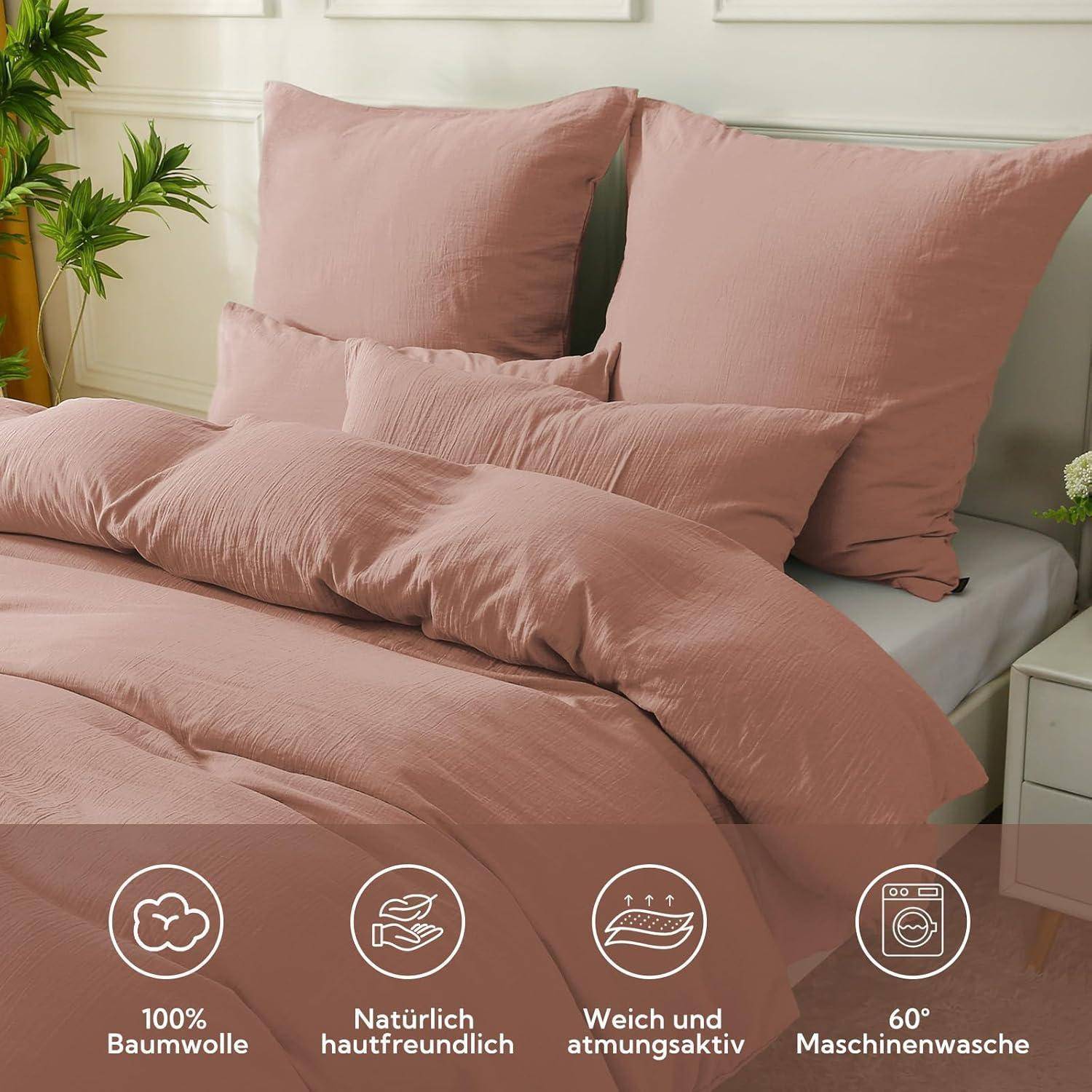 Ein ordentlich gemachtes Bett mit rosa Bettwäsche in einem sonnendurchfluteten Schlafzimmer. Symbole zeigen '100% Baumwolle', 'hautfreundlich', 'atmungsaktiv und feuchtigkeitsregulierend', 'bei 60°C maschinell waschbar'.