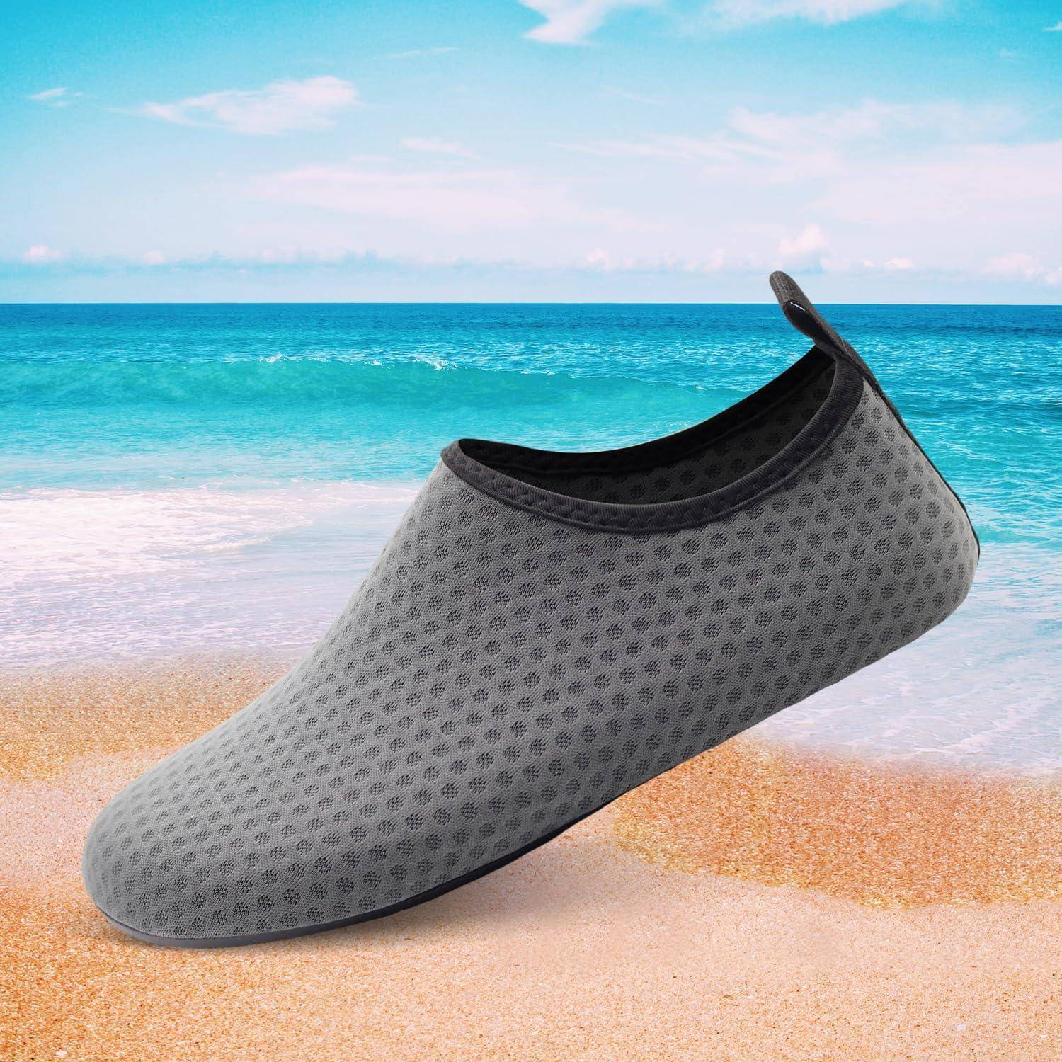 Ein grauer Strandschuh sitzt auf Sand vor der Kulisse eines ruhigen Ozeans und eines teilweise bewölkten Himmels, was eine entspannende Meeresumgebung andeutet.