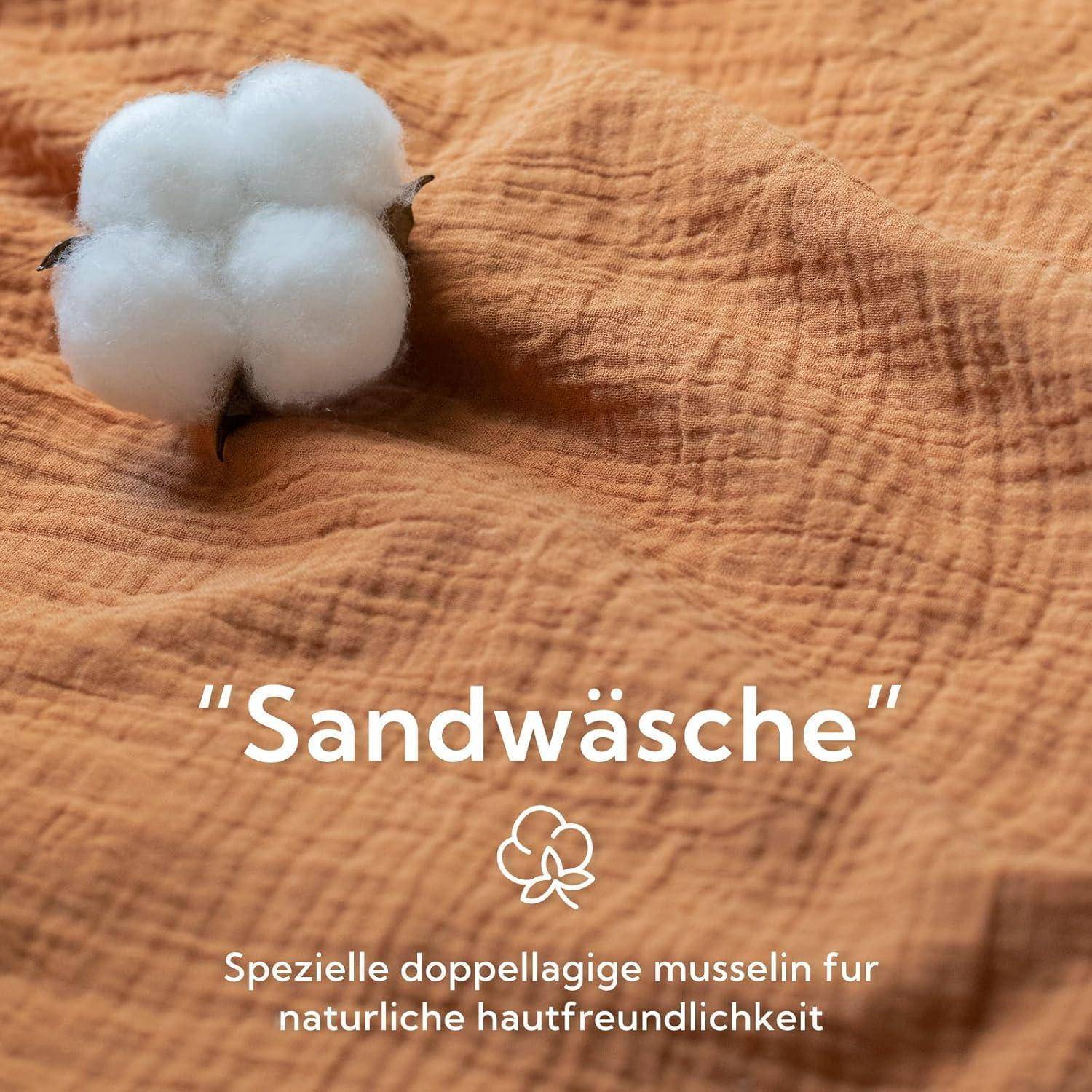 Baumwollkapsel auf strukturiertem Stoffhintergrund mit dem Text 'Sandwäsche'. Beschreibt die sanften, hautfreundlichen Eigenschaften des Stoffes.