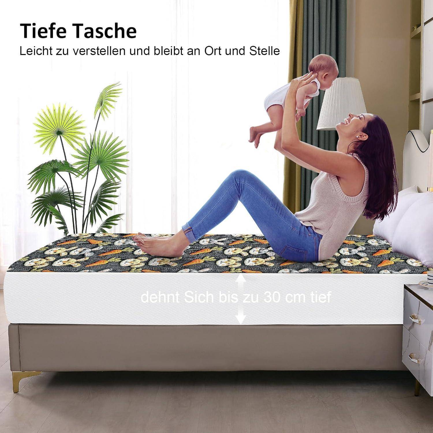 Eine Mutter hebt ihr Baby voller Freude, während sie auf einem Bett mit einem blumenmustergedruckten Spannbettlaken sitzt. Text auf Deutsch hebt Bettlaken mit tiefen Taschen hervor.