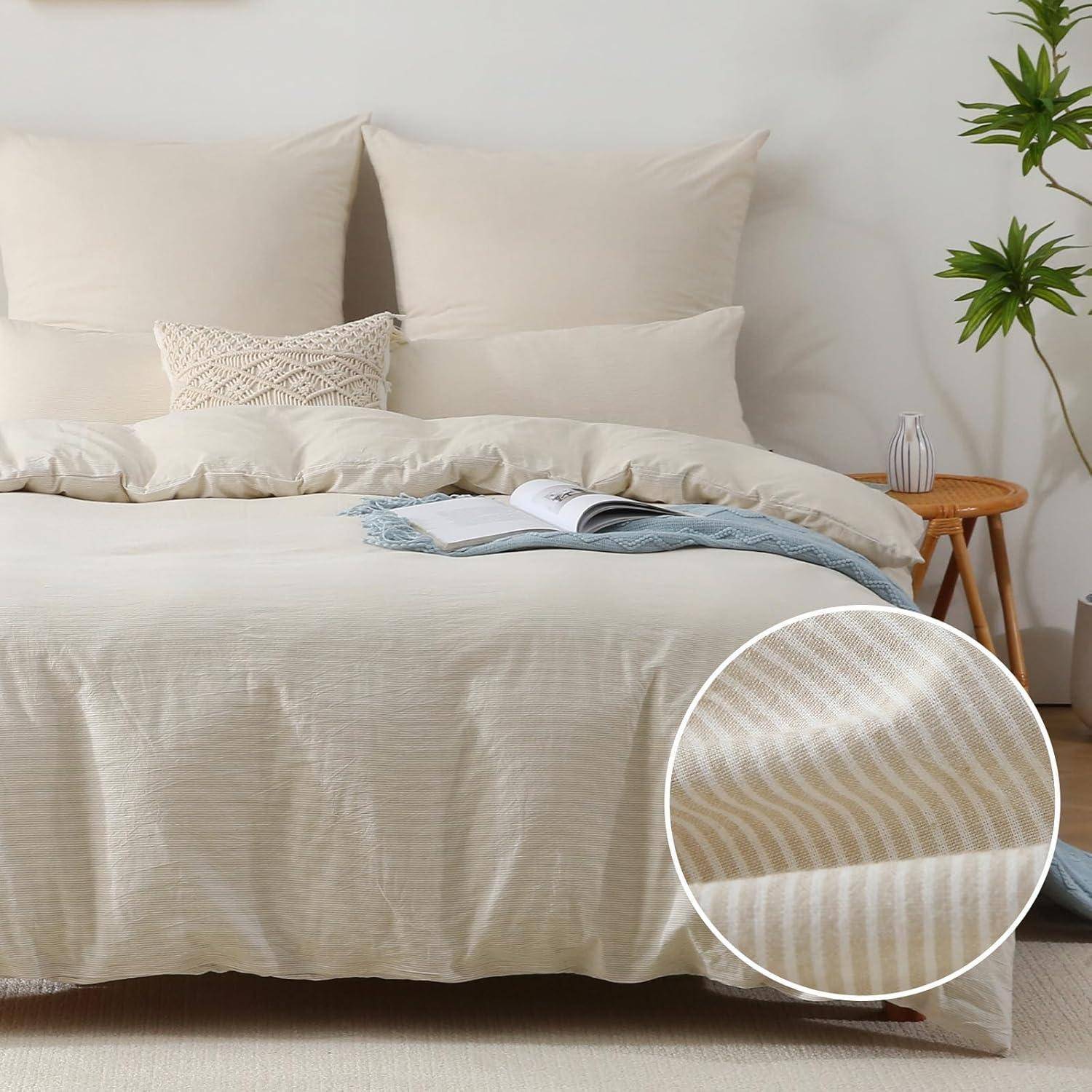 Ein ordentlich gemachtes Bett mit cremefarbenen Kissen und einer Bettdecke. Eine Nahaufnahme zeigt die dezente gestreifte Textur der Bettdecke. Eine kleine Pflanze steht auf einem Beistelltisch.