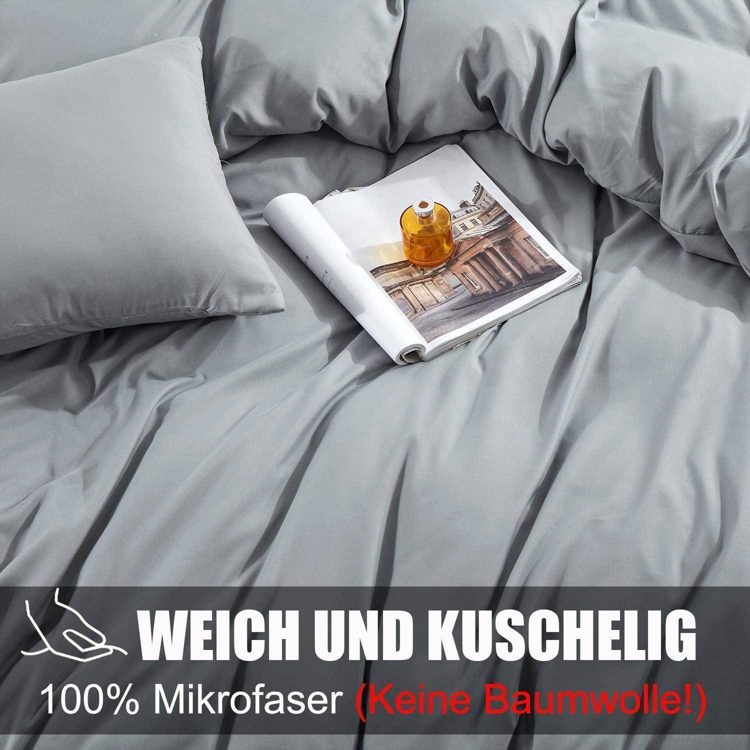 Kissen und Decke aus grauem Mikrofaser auf einem Bett mit einer Zeitschrift und einem Bernsteinglas darauf. Text lautet: 