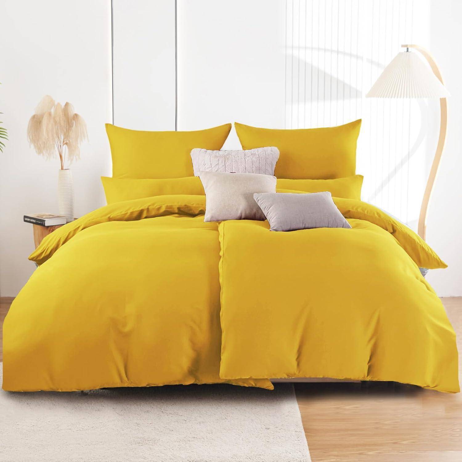 Ein ordentlich gemachtes Bett mit leuchtend gelber Bettwäsche, zwei großen gelben Kissen und beige-farbenen Zierkissen in einem hell erleuchteten Raum mit einem Nachttisch.