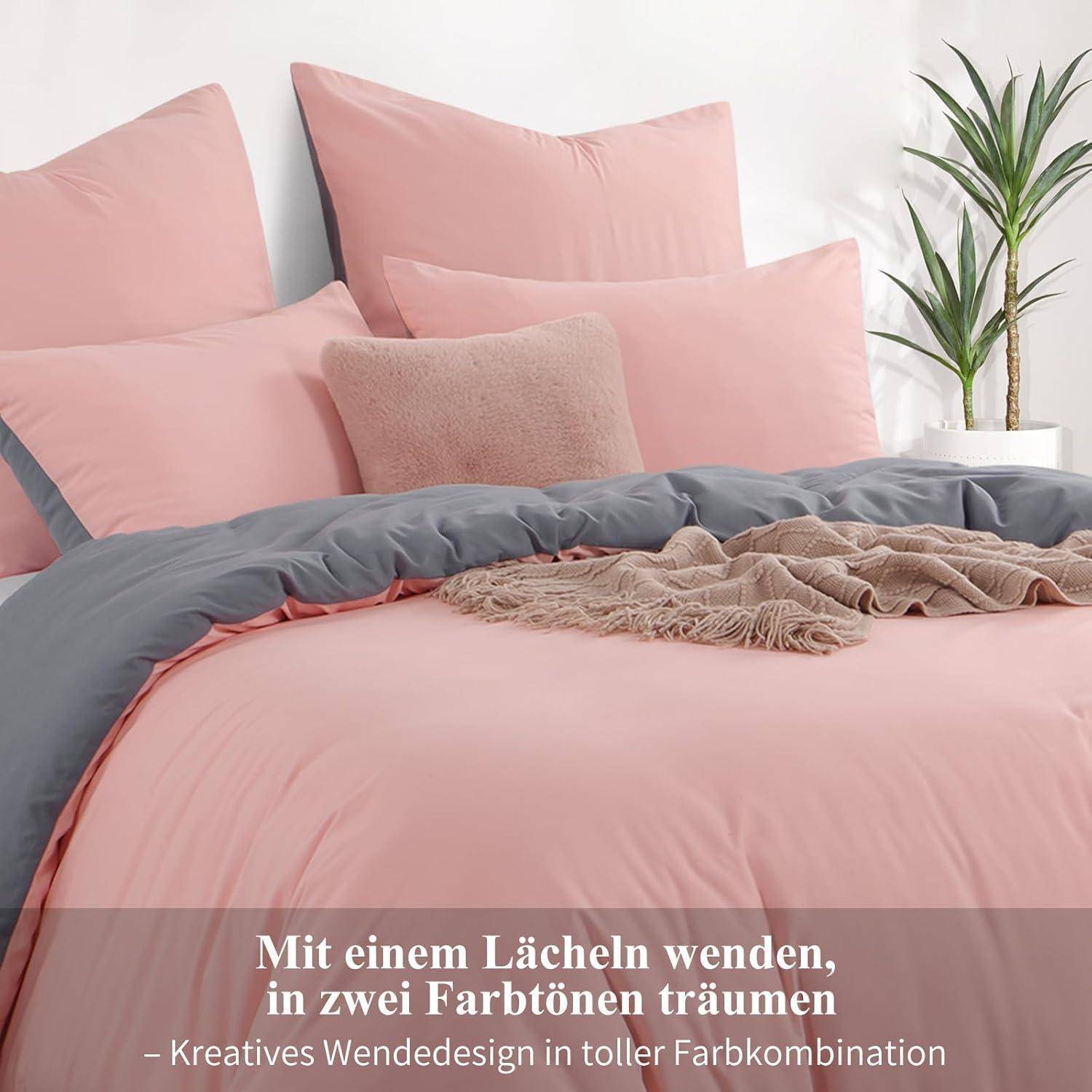 Ein Bett mit rosa und grauer Bettwäsche, einschließlich Kissen und einer Decke, wird gezeigt. Text lautet: 'Mit einem Lächeln wenden, in zwei Farbtönen träumen.