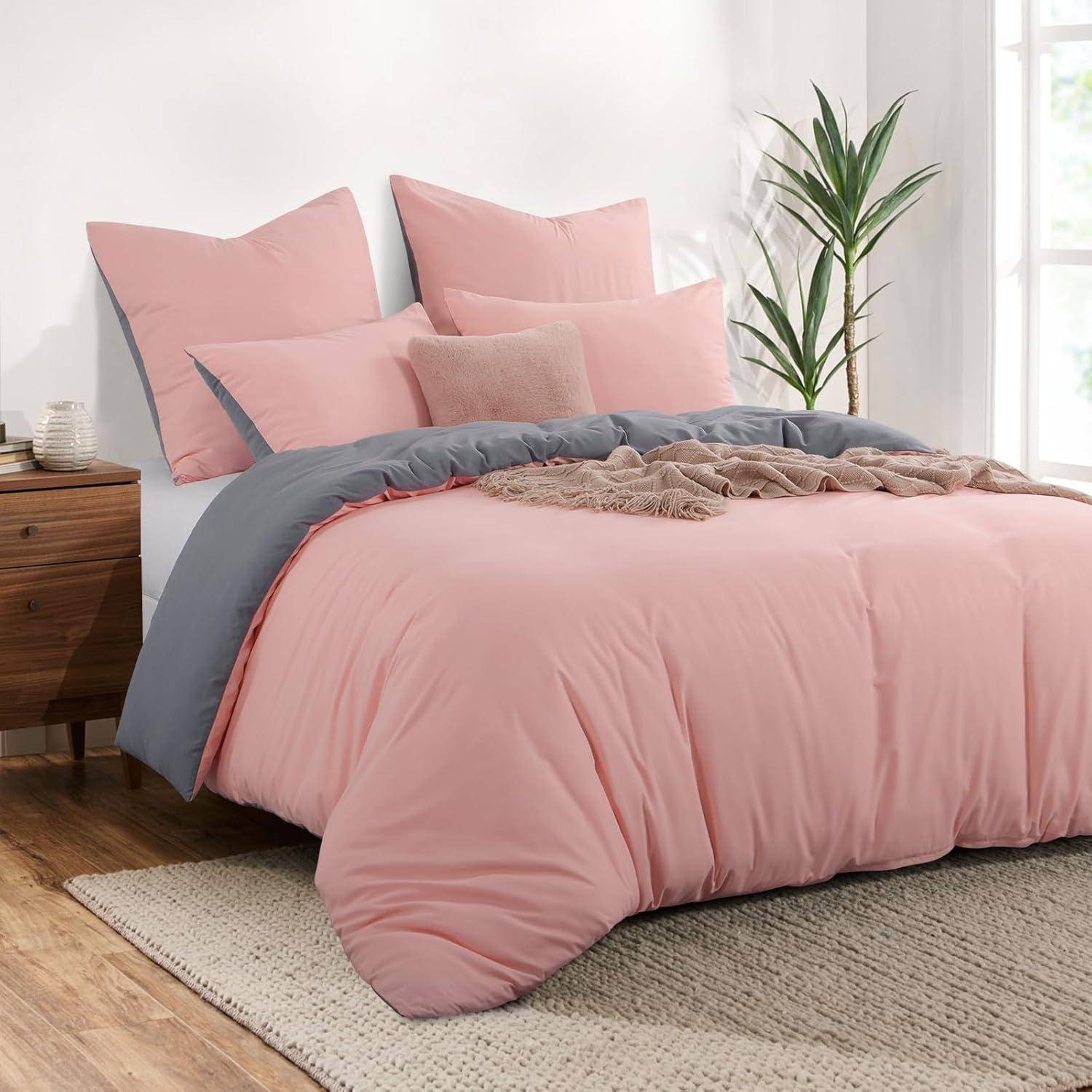 Ein ordentlich gemachtes Bett mit rosa Bettwäsche, Kissen und einer Decke. Rechts steht eine Pflanze, und links befindet sich ein Holznachttisch mit Büchern.