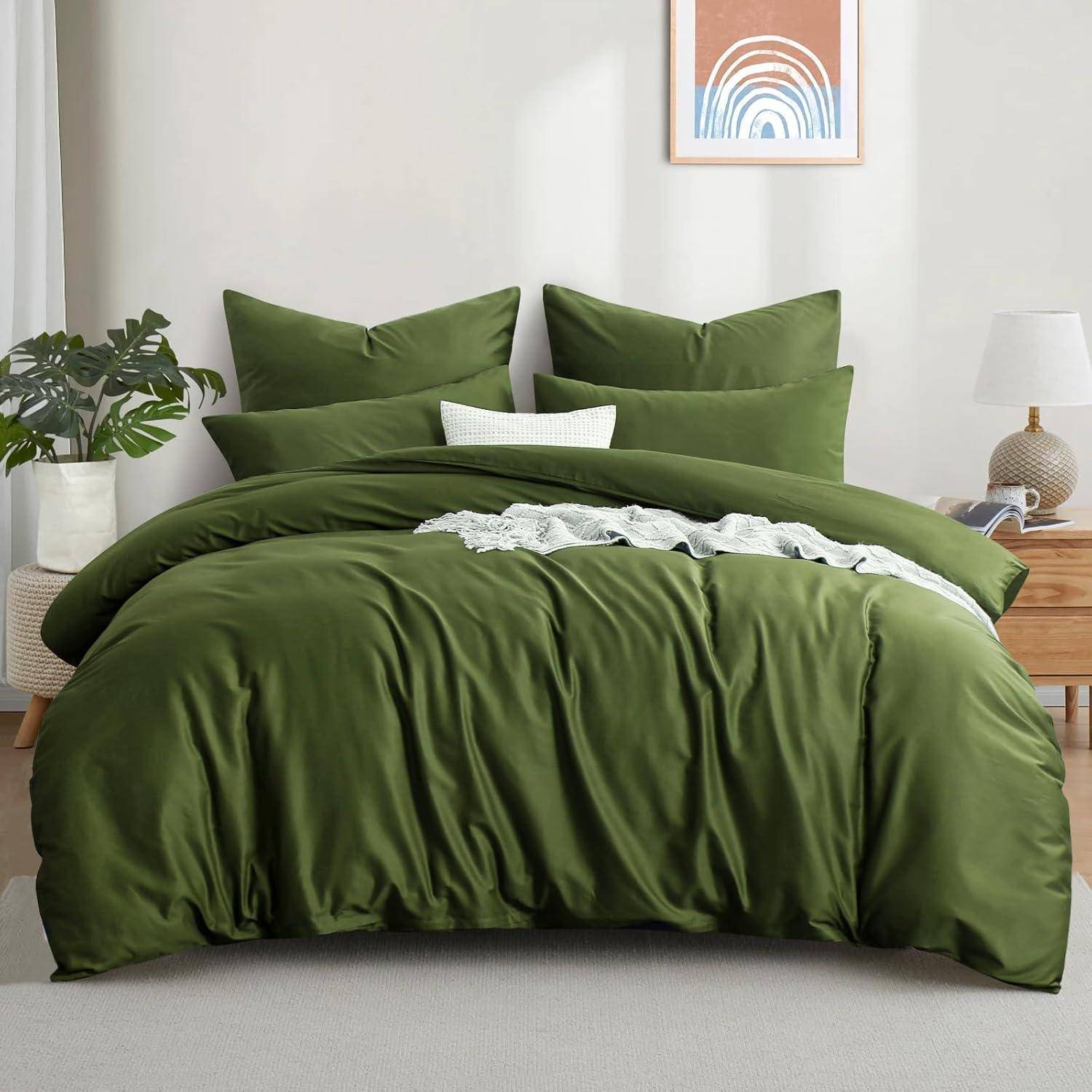 Ein ordentlich gemachtes Bett mit einem grünen Bettdecken und Kissen, mit weißer Spitze als Akzent oben drauf. Eine Pflanze und eine Lampe auf einem Beistelltisch, gerahmte Kunstwerke an der Wand.
