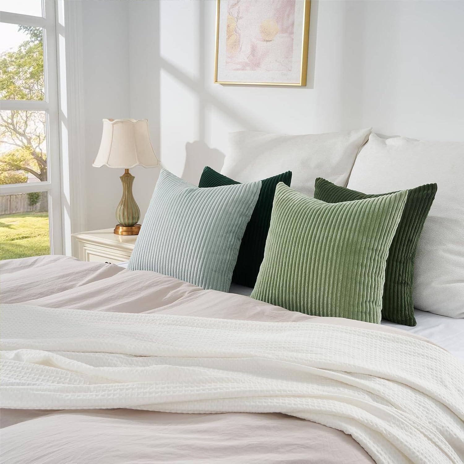 Ein gemütliches Schlafzimmer mit einem ordentlich gemachten Bett, das mit grünen und weißen Kissen und weichen Decken ausgestattet ist, einem Nachttisch und einer Lampe, durch dessen Fenster Sonnenlicht hereinströmt.