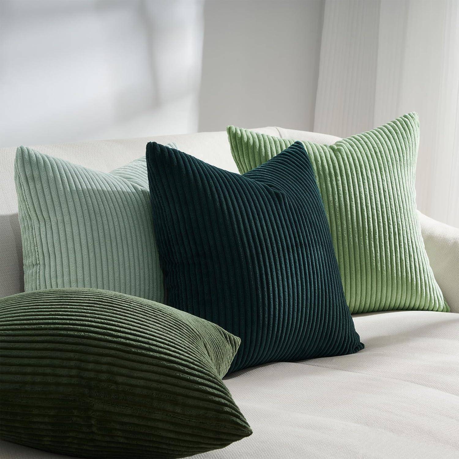 Drei Cordkissen in verschiedenen Grüntönen sind auf einem weißen Sofa angeordnet und verstärken die gemütliche und stilvolle Atmosphäre des Raumes.