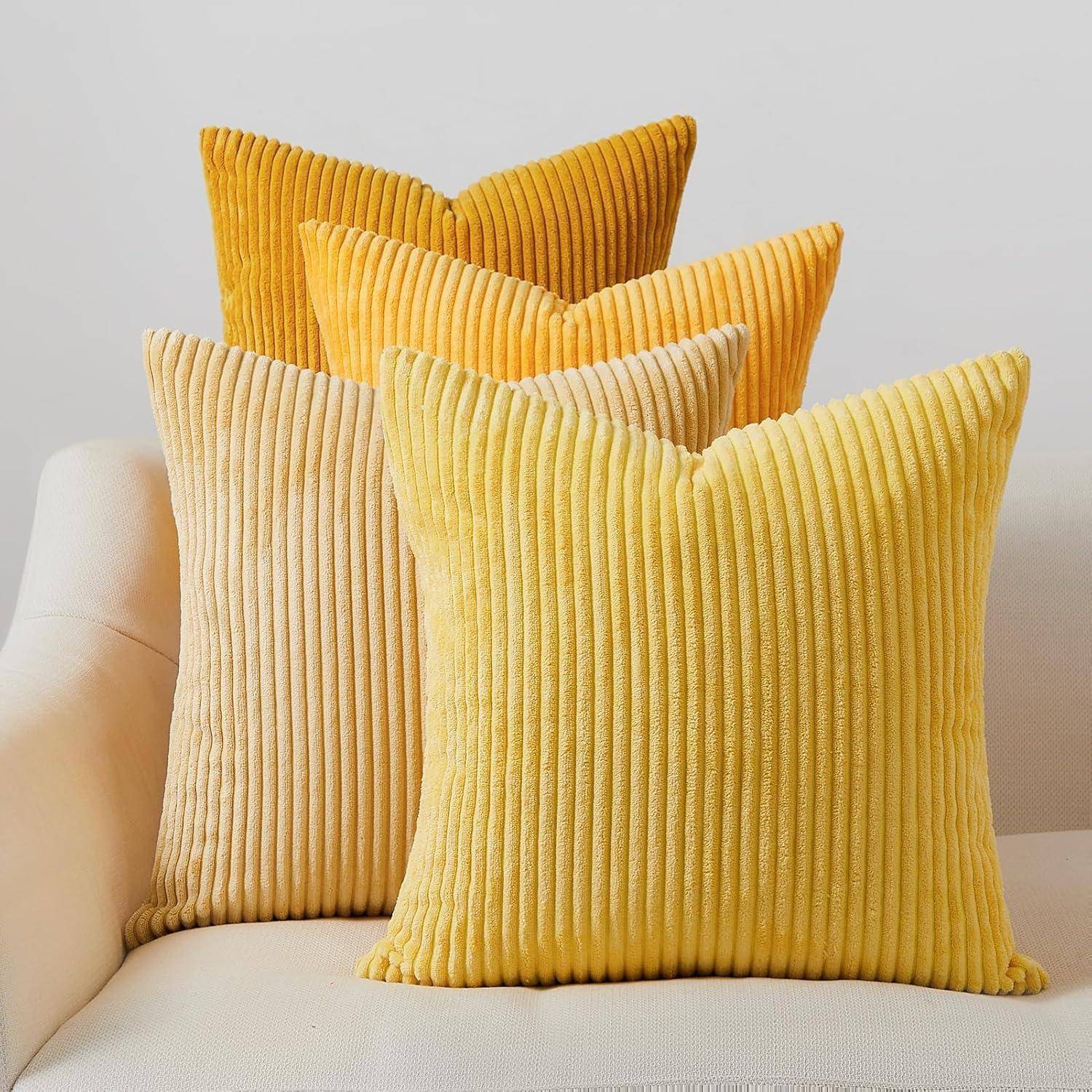 Gelbe und beige gestreifte Zierkissen, ordentlich auf einem weißen Sofa angeordnet, die eine gemütliche und einladende Atmosphäre schaffen.