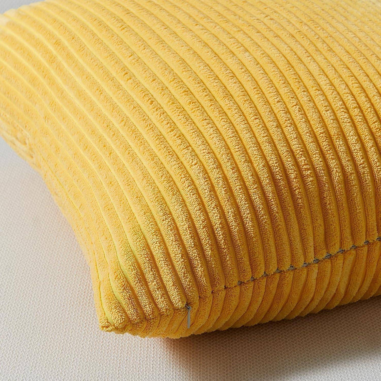 Ein gelbes, geripptes Kissen ruht auf einer hellen Stoffoberfläche und hebt sein strukturiertes Design und seine gemütliche Erscheinung hervor.
