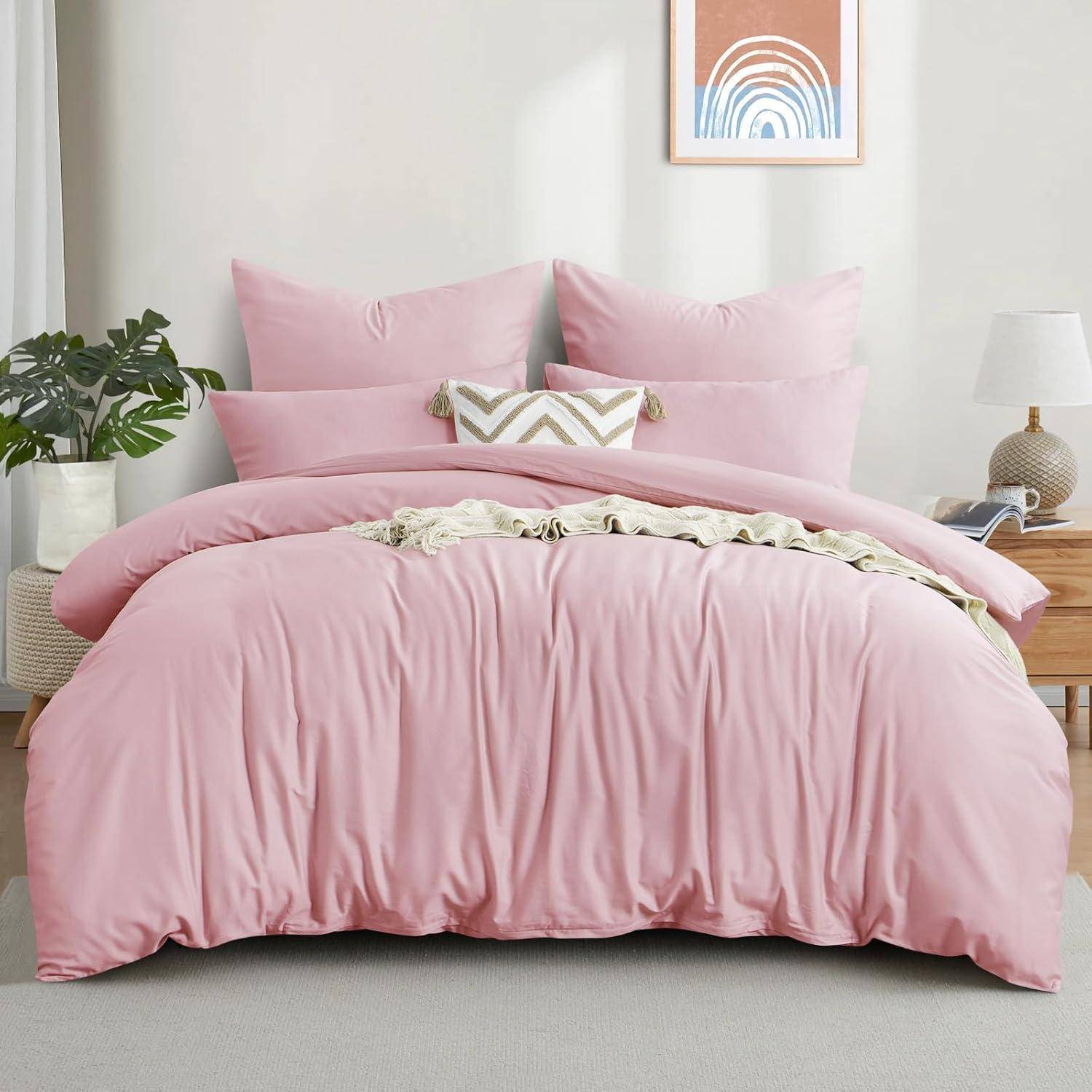 Ein ordentlich hergerichtetes Bett mit rosa Bettwäsche, dekorativen Kissen und einem gemusterten Akzentkissen in einem gemütlichen Raum mit einer Pflanze und Kunstwerk an der Wand.