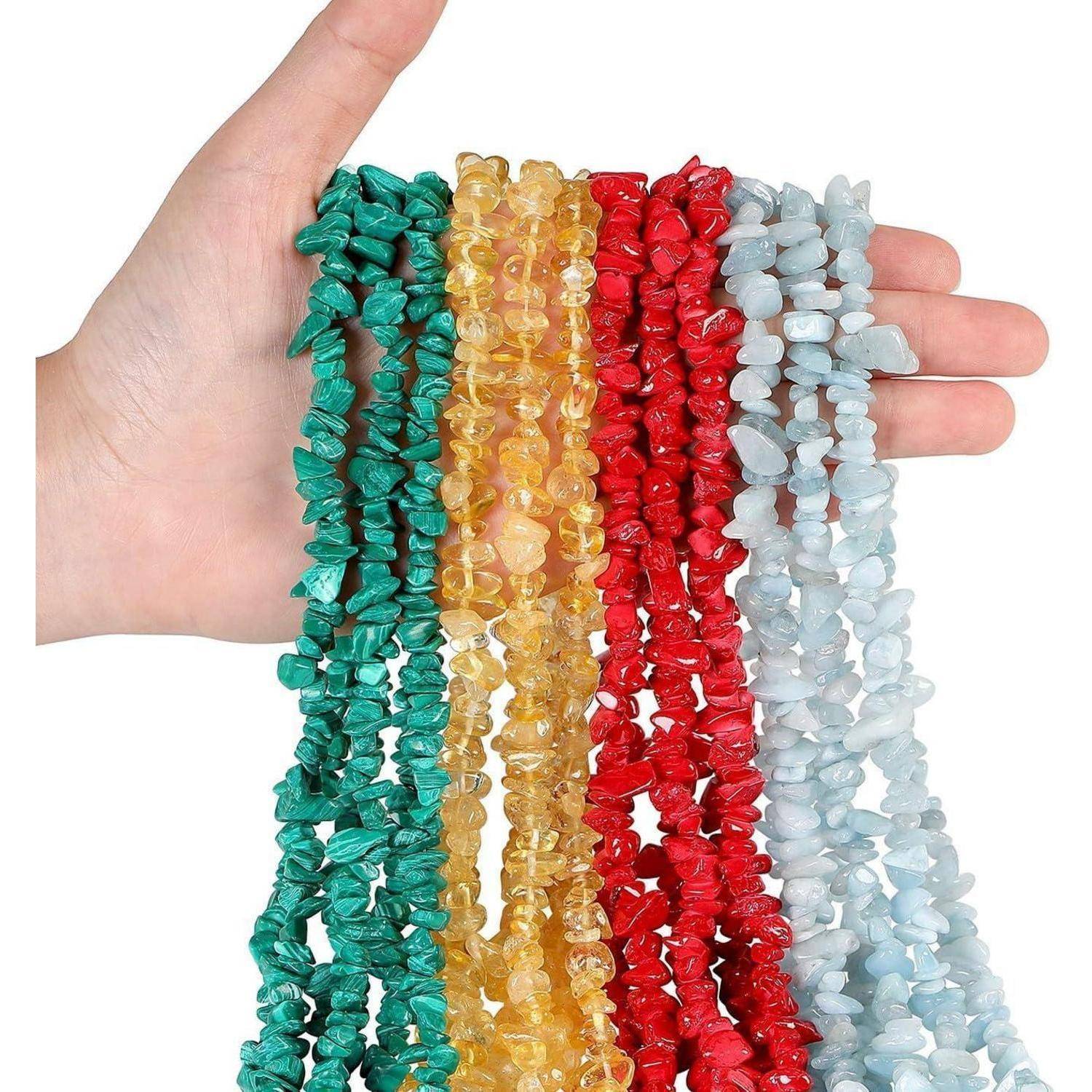 Eine Hand hält Stränge bunter Edelstein-Splitperlen, darunter Türkis, Gelb, Rot und Hellblau, und zeigt Vielfalt und Textur.