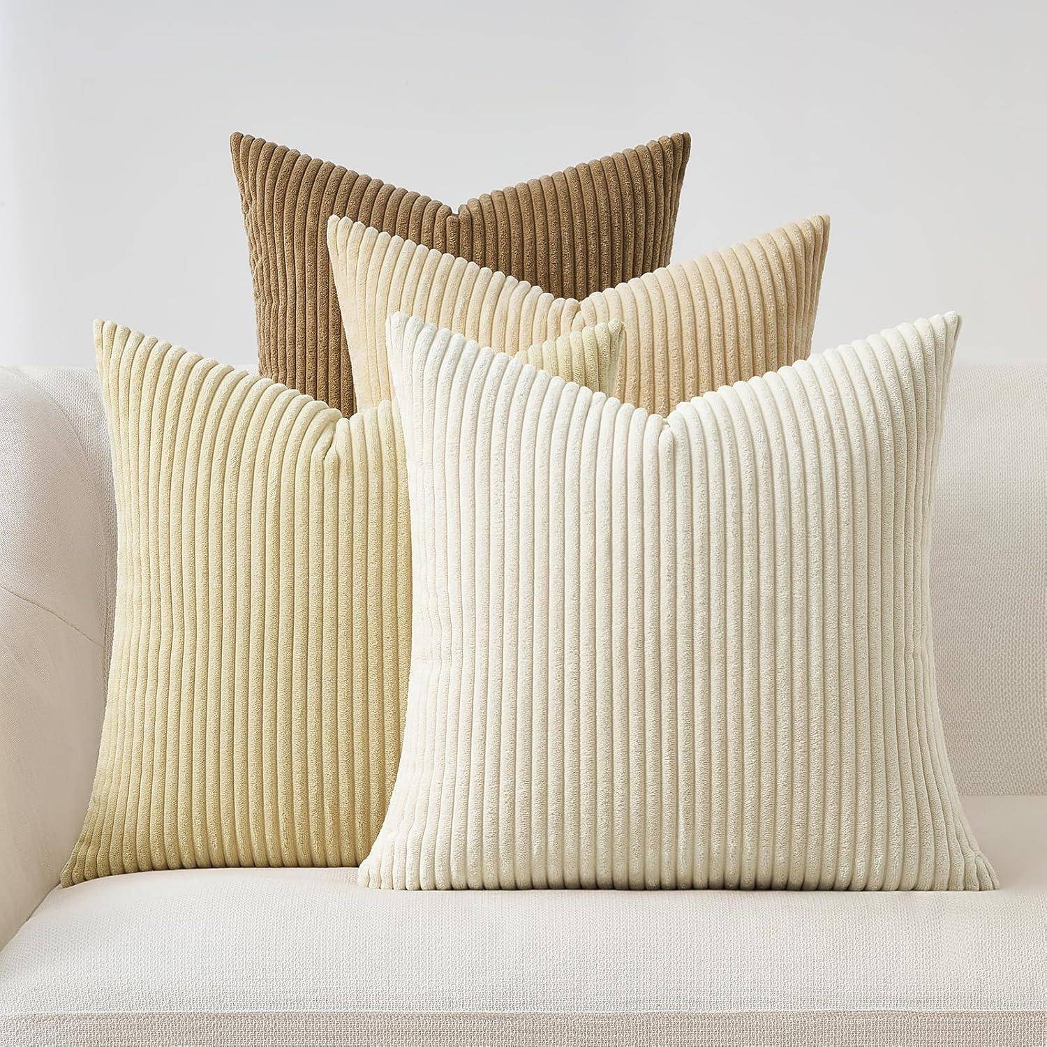 Drei gerippte Textur-Kissen in Schattierungen von Creme, Beige und Braun sind auf einem hellen Sofa angeordnet und verleihen ihm einen gemütlichen, stilvollen Look.