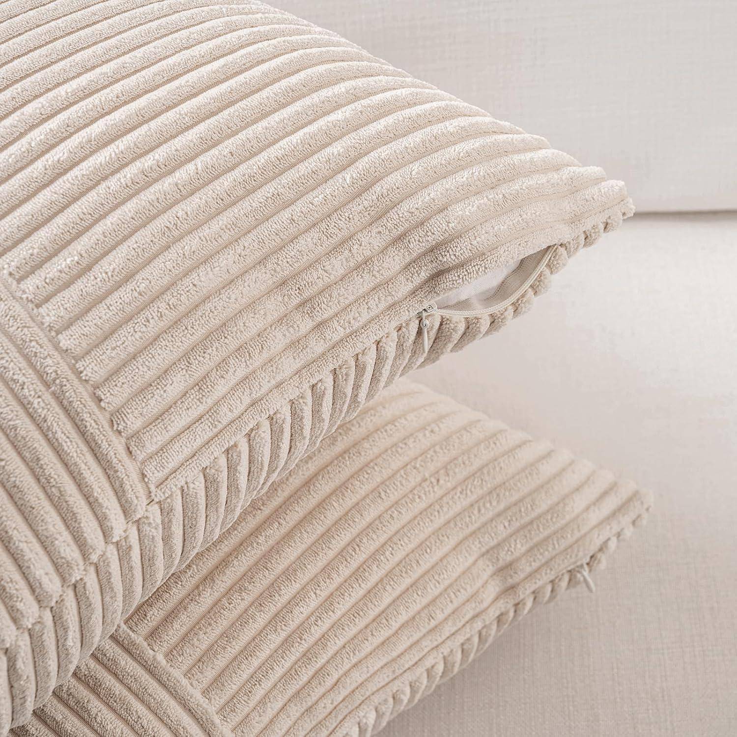 Zwei beige Cordkissen sind auf einem hellgefärbten Sofa gestapelt und zeigen ihre strukturierte Stoffoberfläche sowie ihr weiches Erscheinungsbild.