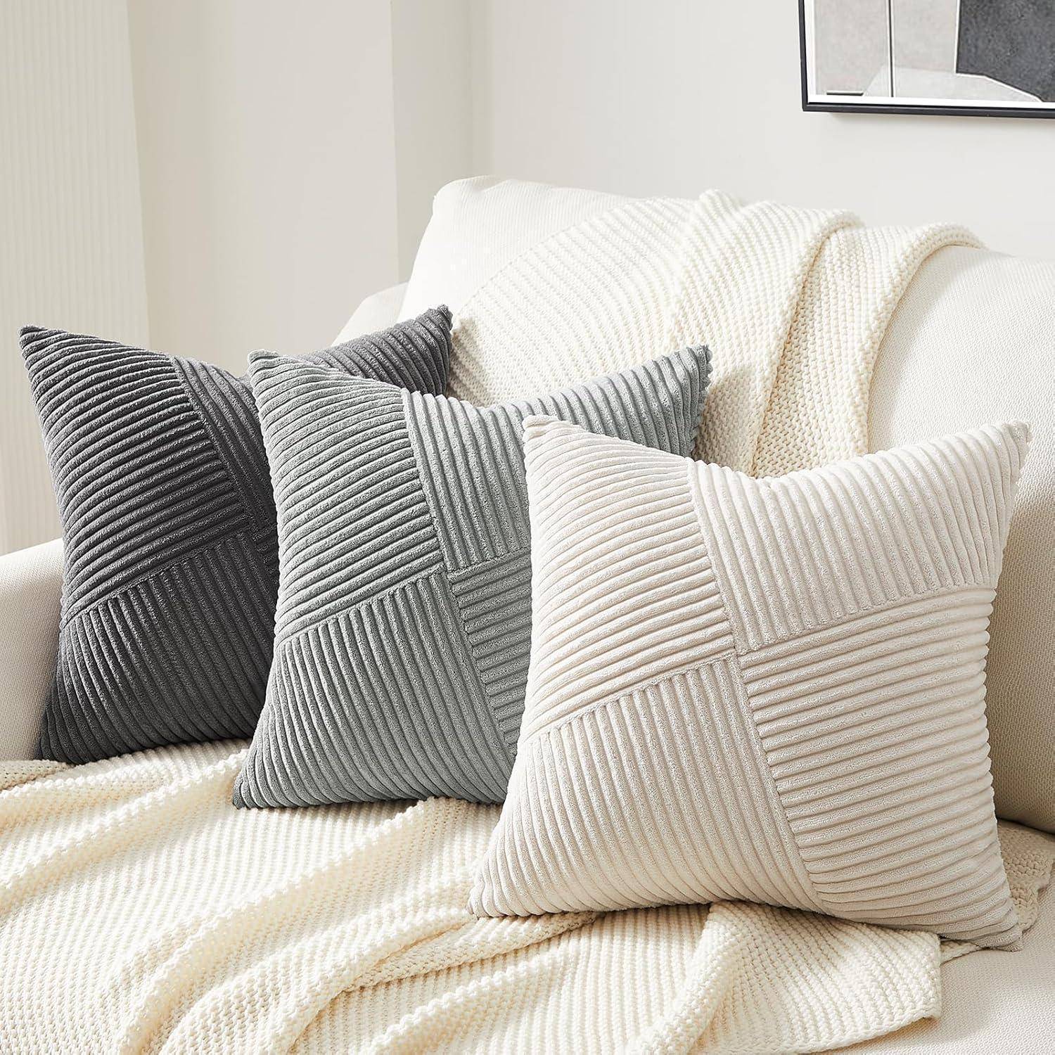Creme- und graue Kissen mit Strukturmustern, die auf einem cremefarbenen Sofa angeordnet sind und eine gemütliche und einladende Atmosphäre im Wohnzimmer schaffen.
