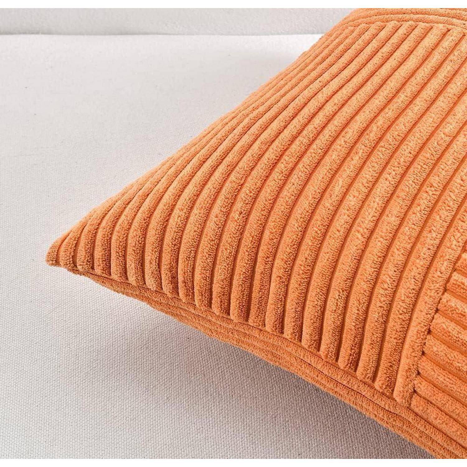 Eine strukturierte, orangefarbene Kissen mit vertikalen gerippten Streifen, platziert auf einer helltonigen Oberfläche.