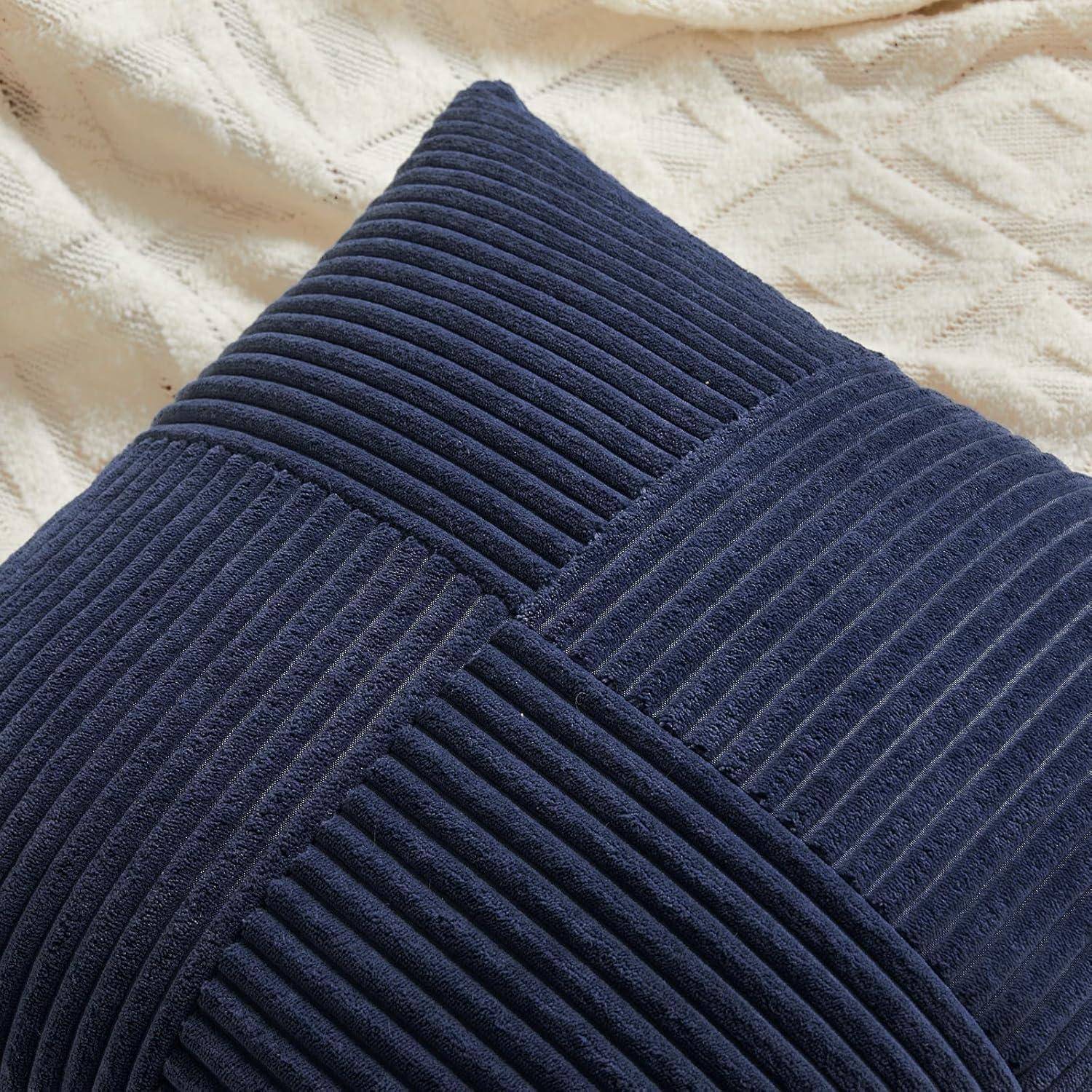 Ein marineblauer, gerippter quadratischer Kissenbezug ruht auf einer cremefarbenen strukturierten Decke.
