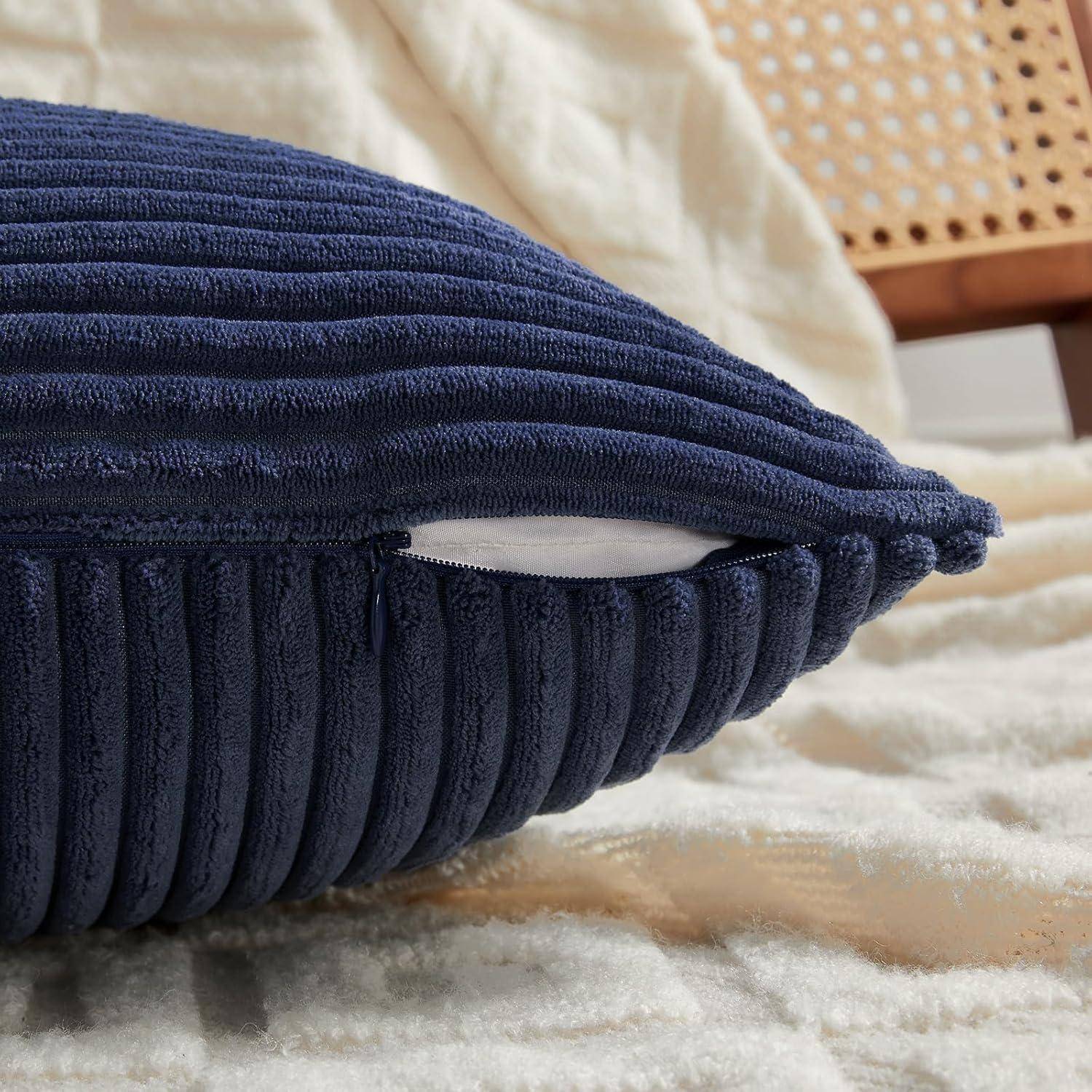 Ein blauer, gerippter Kissenbezug mit Reißverschluss auf einer cremefarbenen, strukturierten Decke, die auf einem Bett liegt.