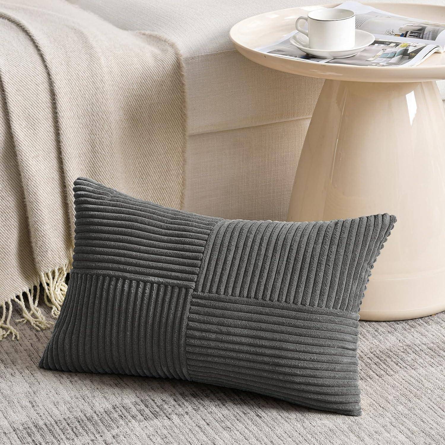 Ein grauer strukturierter Kissenbezug, der auf einem beigen Sofa ruht, mit einem weißen Beistelltisch, auf dem eine Tasse und eine Zeitung stehen.