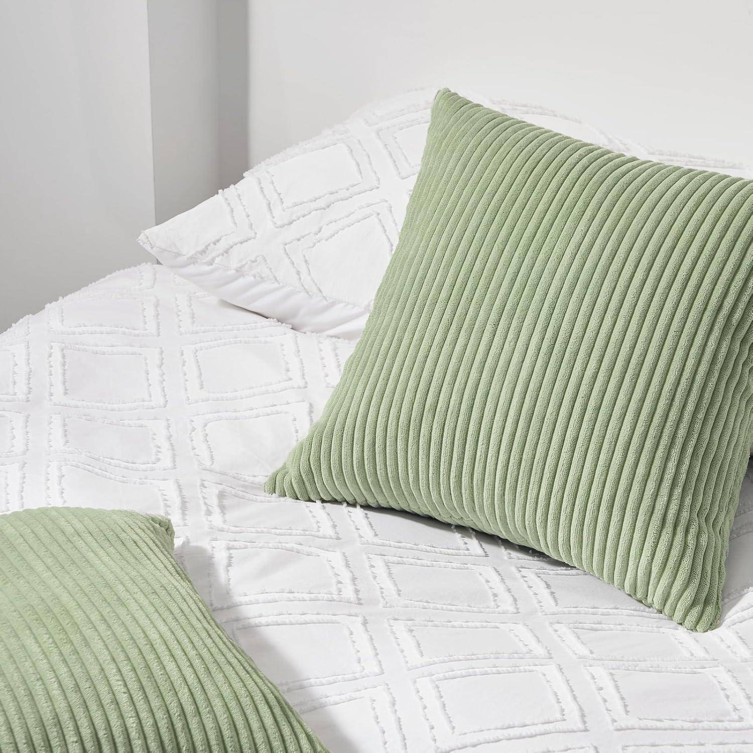 Ein Bett mit einem weißen strukturierten Bettbezug und zwei grünen Cordkissen.