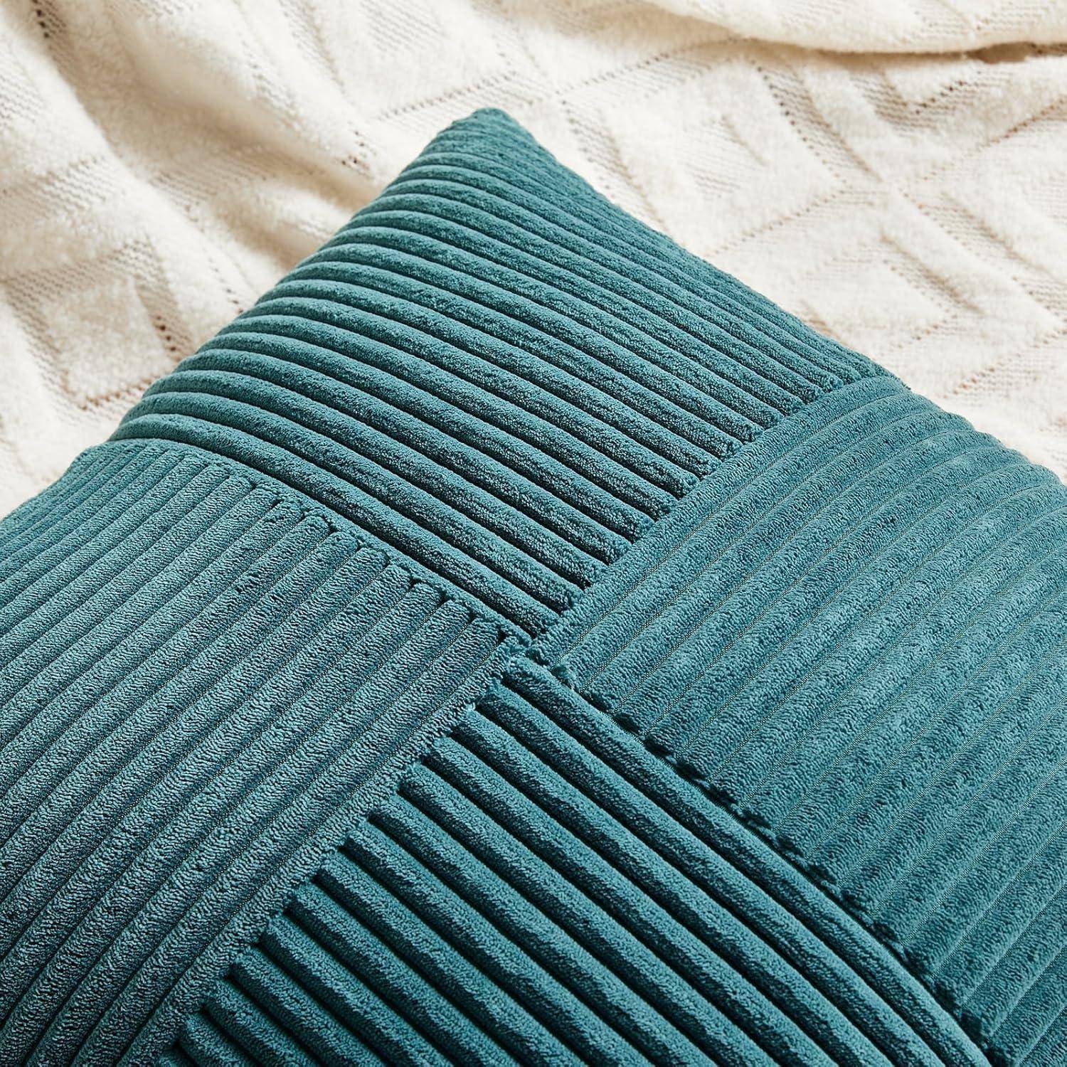 Ein strukturiertes türkisfarbenes Kissen mit geripptem Quadratmuster ruht auf einem cremefarbenen gestrickten Decken-Hintergrund.