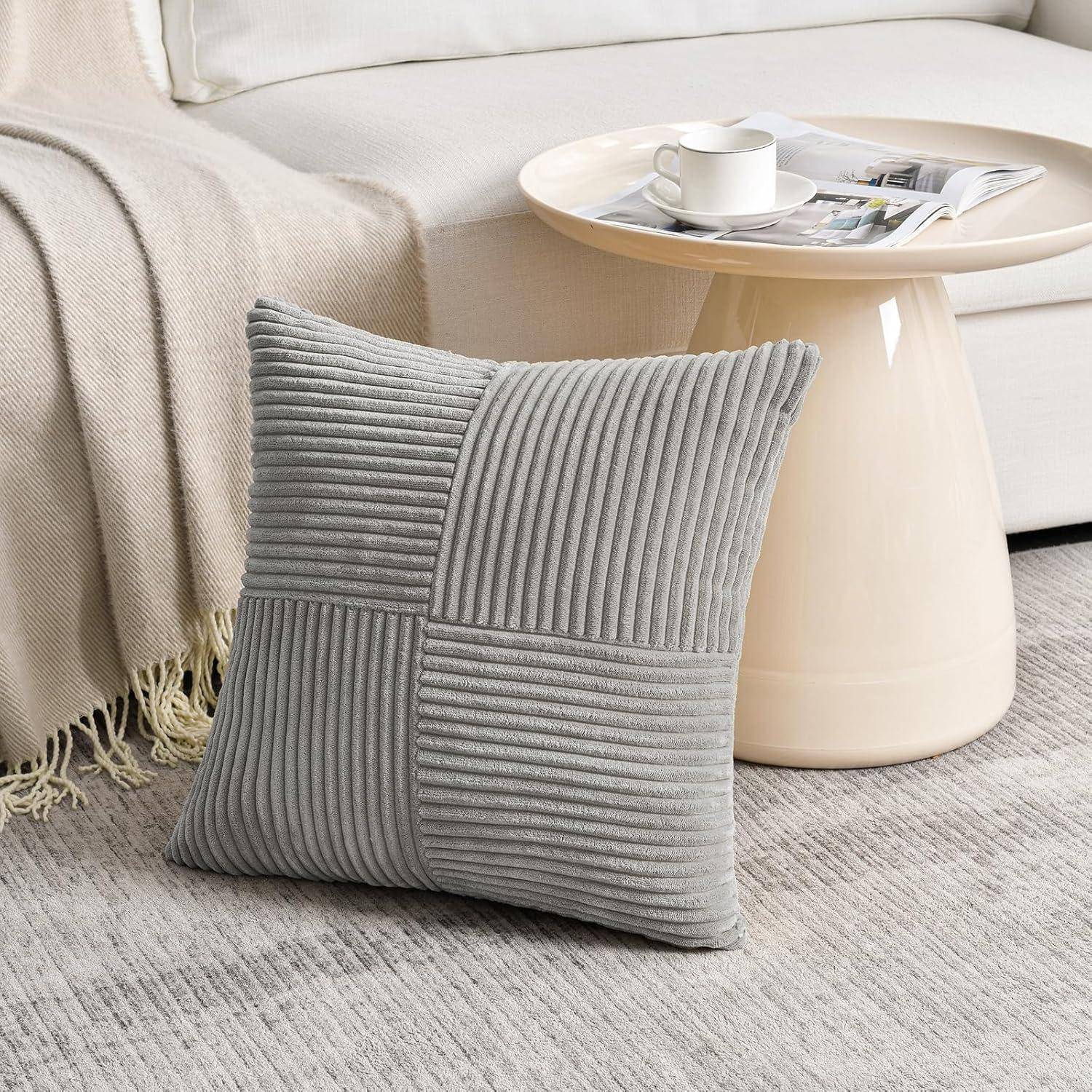 Ein grau gestreiftes Kissen auf einem Teppich, neben einem runden Couchtisch mit einer Zeitschrift und einer Tasse, in einer gemütlichen Wohnzimmeratmosphäre.