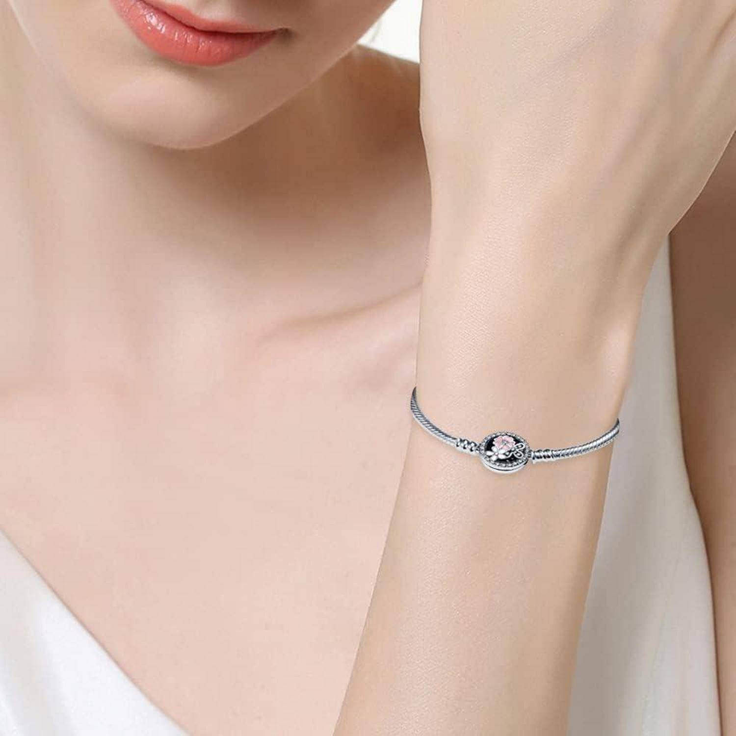 Eine Person, die ein schlichtes silbernes Armband mit einem runden dekorativen Element trägt, abgebildet vor einem weißen Hintergrund.