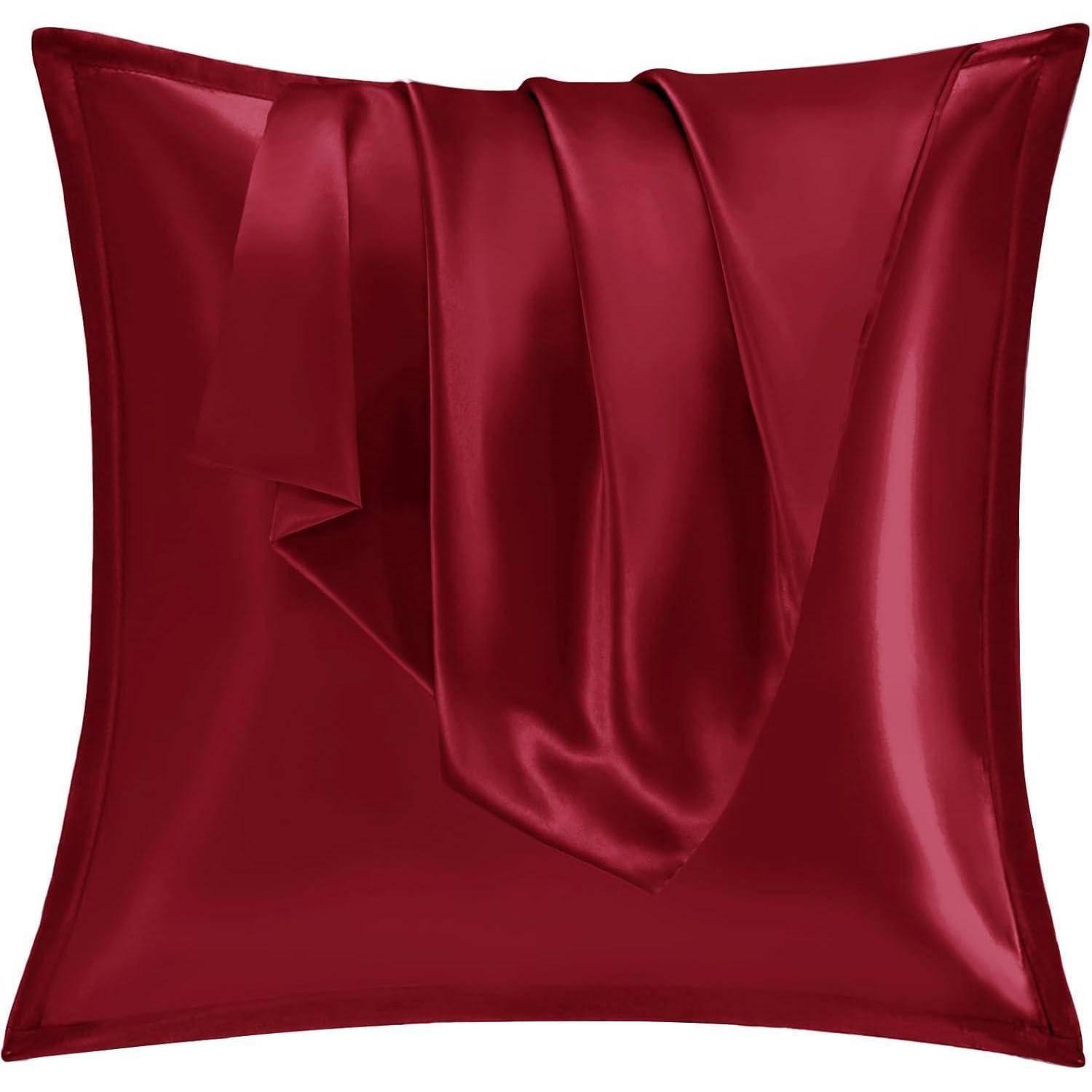 Ein roter Seidensatin-Kissenbezug, der über einem quadratischen Kissen drapiert ist. Der glänzende Stoff reflektiert das Licht und betont seine glatte, seidig weiche Textur.
