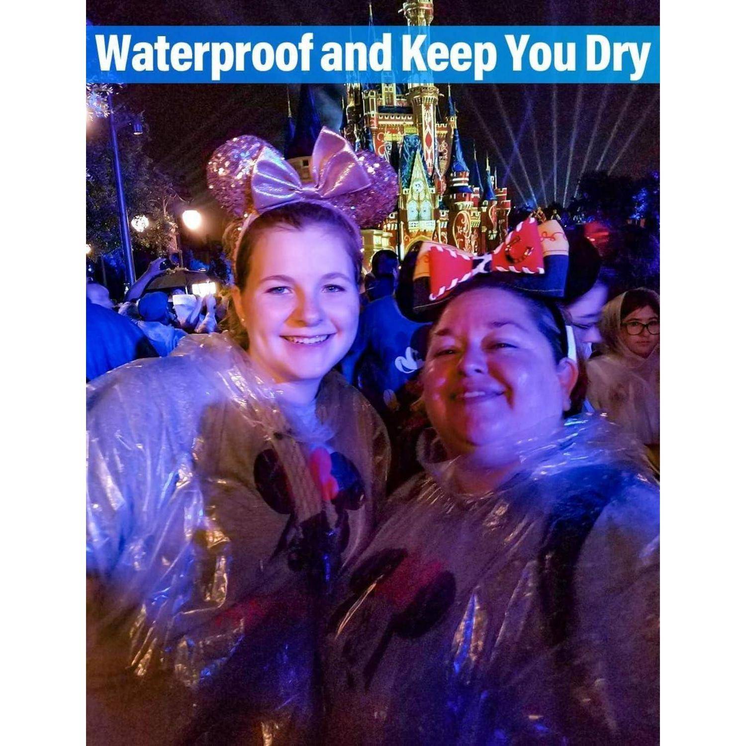 Zwei Personen in Ponchos und Mauseohren lächeln nachts vor einem beleuchteten Schloss, mit dem Text 'Wasserdicht und hält Sie trocken' darüber.