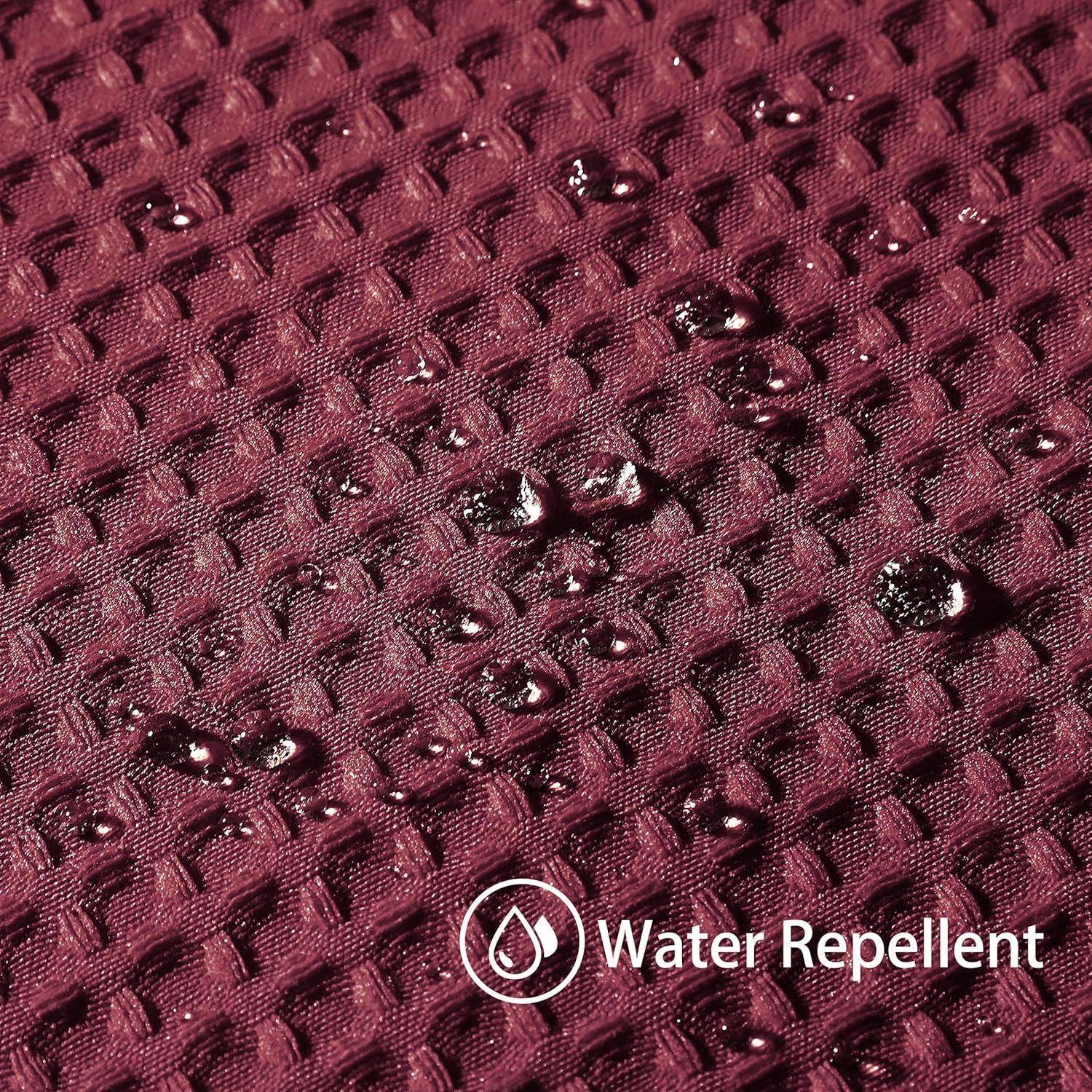 Wassertropfen perlen auf marronefarbenem Stoff mit strukturiertem Muster und zeigen dabei die wasserabweisende Eigenschaft des Materials.
