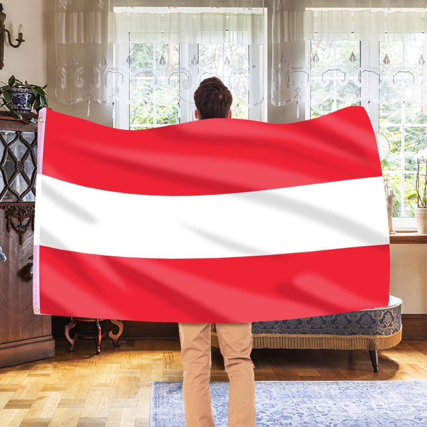 Eine Person hält eine große rot-weiß gestreifte Flagge in Innenräumen und steht vor einem Fenster mit Spitzengardinen.