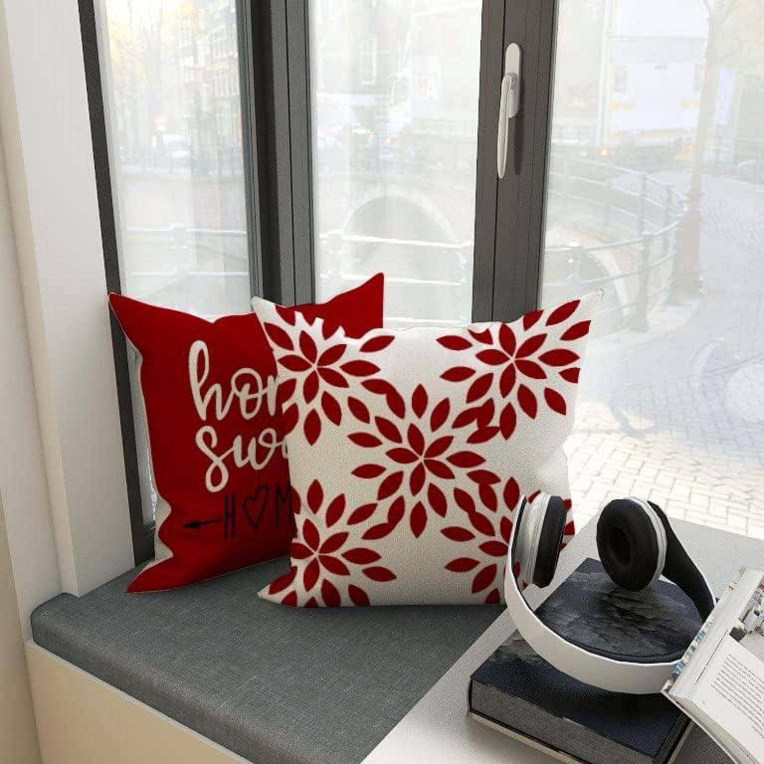 Kissen mit Feiertagsmotiven liegen auf einer Fensterbank mit Blick auf einen Kanal. Kopfhörer und Bücher liegen in der Nähe und schaffen eine gemütliche Atmosphäre.