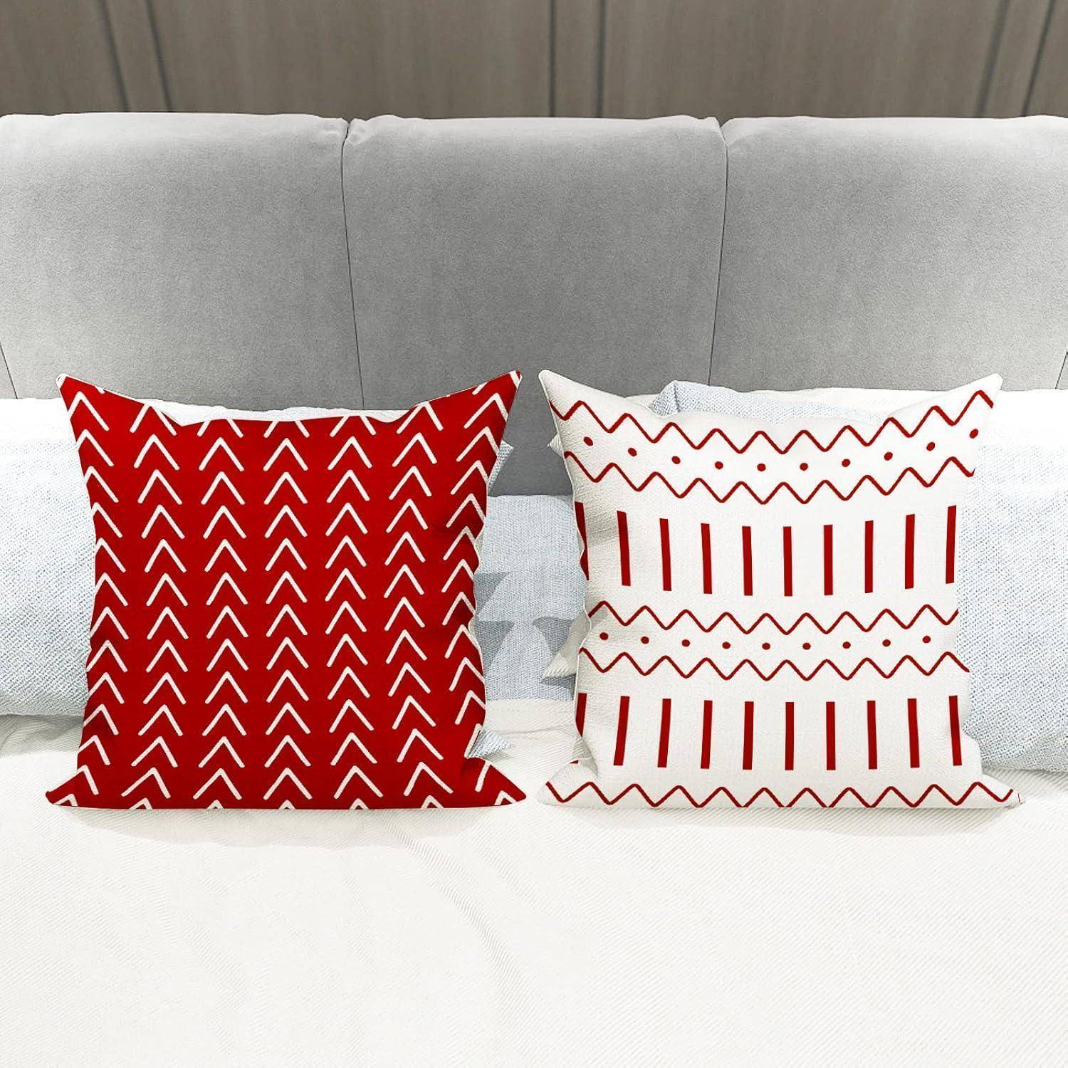 Zwei Zierkissen auf einem hellgrauen Sofa, eines mit roten Zickzackmuster und das andere mit roten geometrischen Designs.