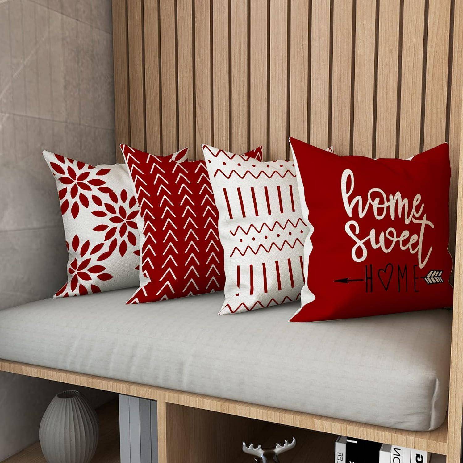 Kissen auf einer Bank mit roten und weißen geometrischen und floralen Mustern. Ein Kissen zeigt den Text 