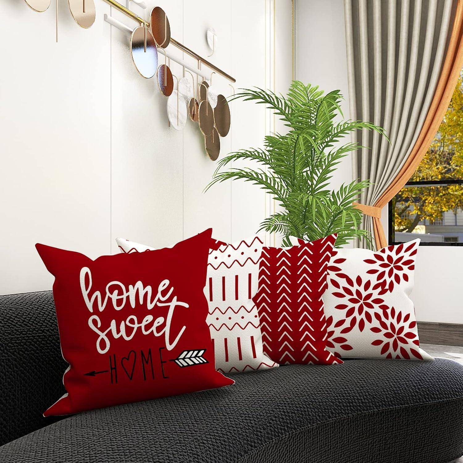 Ein gemütliches Wohnzimmer mit einem grauen Sofa, das rote und weiße Zierkissen trägt, darunter eines mit dem Text 