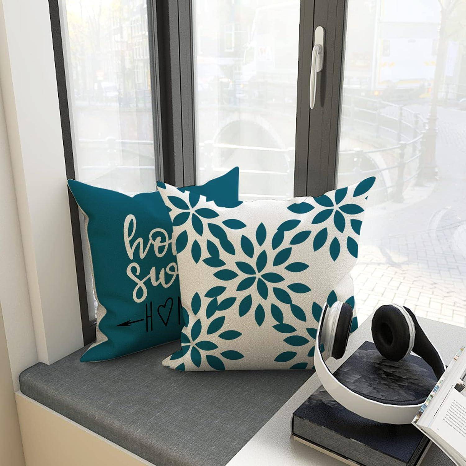 Ein Fensterplatz ist mit zwei dekorativen Kissen ausgestattet, eines mit einem Blumenmuster und ein anderes mit der Aufschrift „home sweet home
