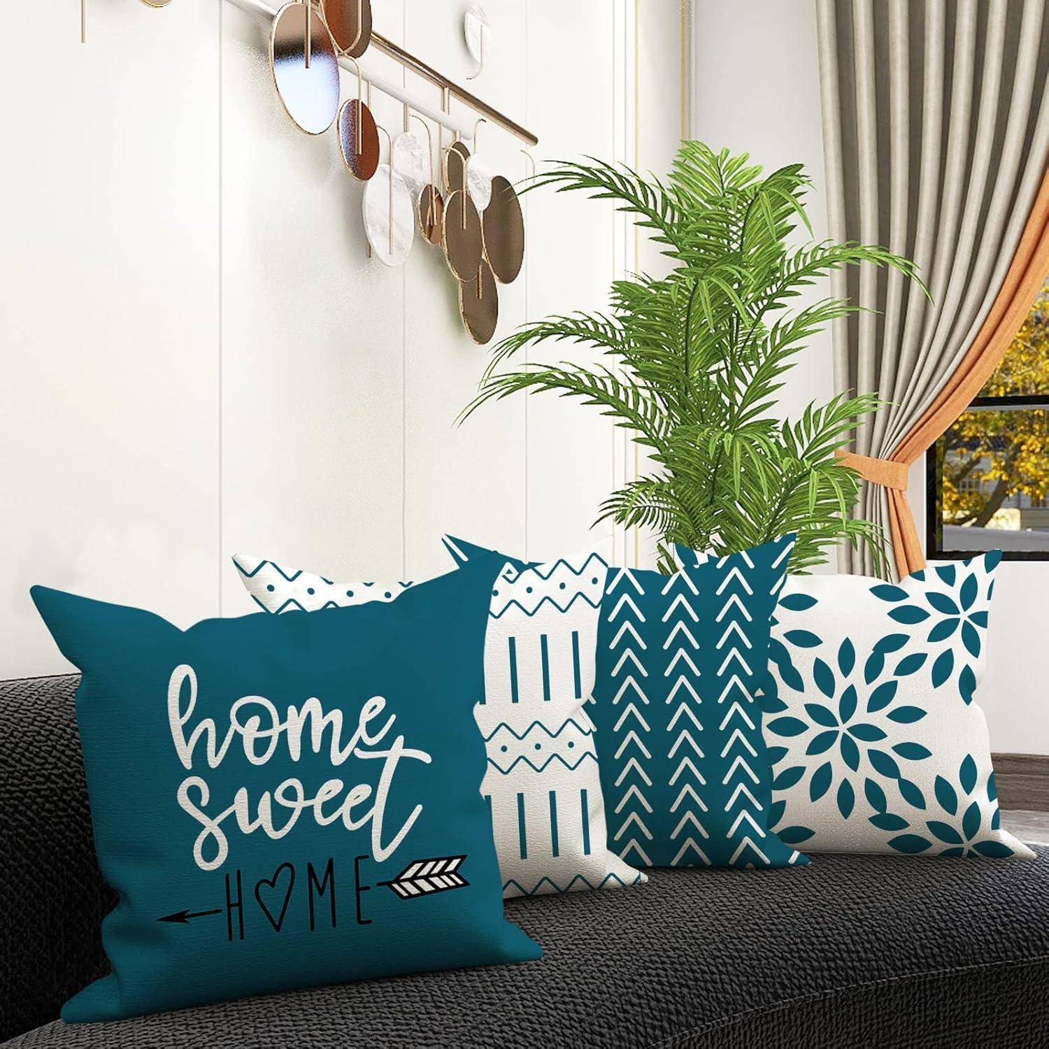 Zierkissen auf einem Sofa mit verschiedenen blauen und weißen Mustern; eines davon trägt die Aufschrift „Zuhause süß Zuhause