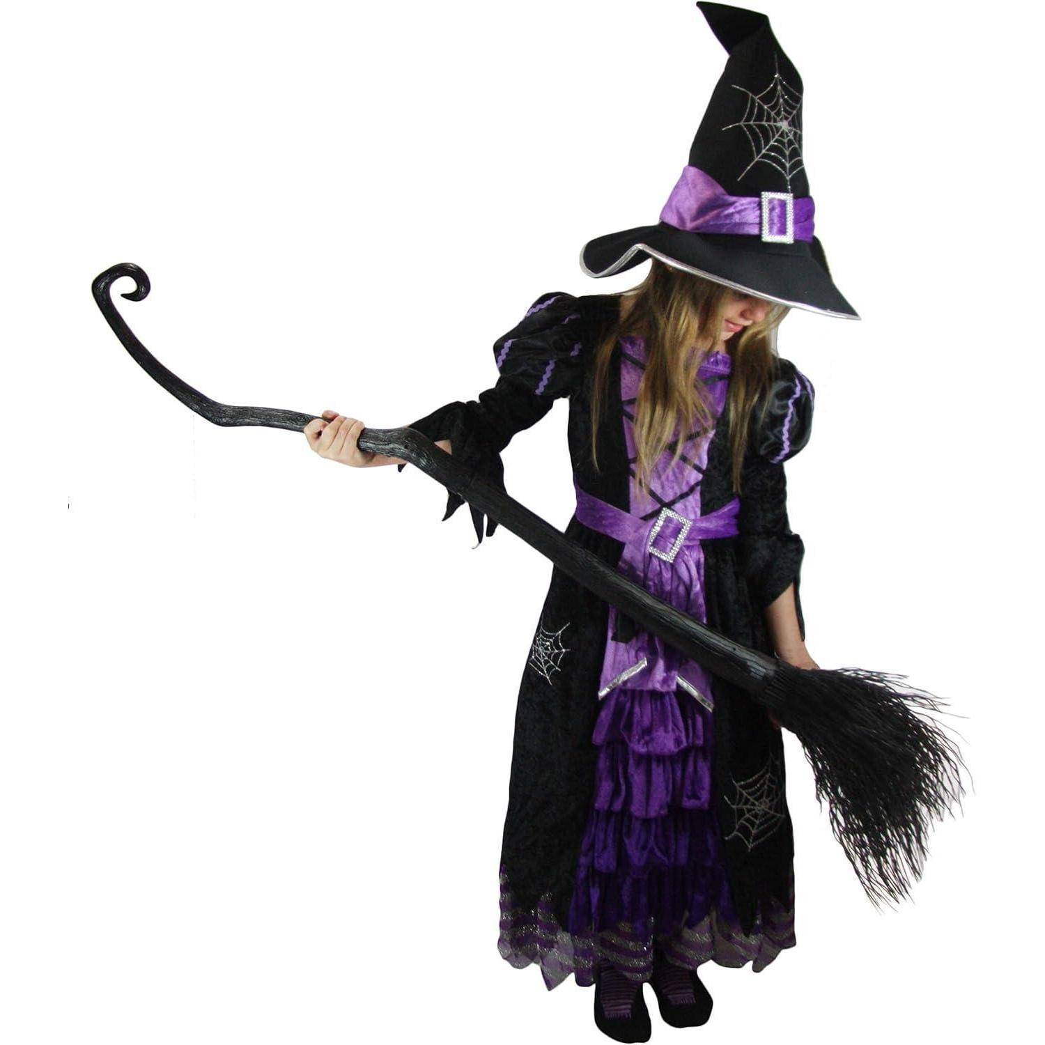 Ein Kind in einem Hexenkostüm, mit spitzer Mütze und einem Besen in der Hand, steht mit nach unten gerichtetem Blick und präsentiert eine Halloween-Kleidung.