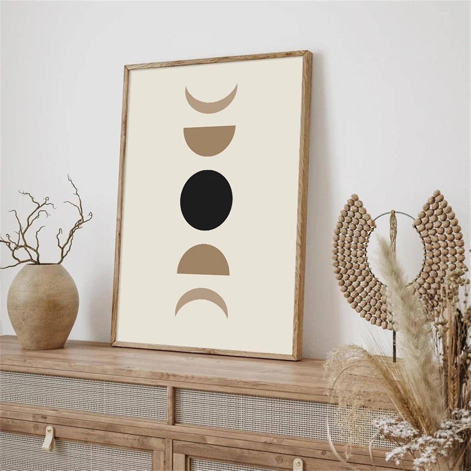 Gerahmte abstrakte Kunst mit einem zentralen schwarzen Kreis, umgeben von sichelförmigen Formen in einer neutralen Umgebung mit natürlichen Dekorationselementen.